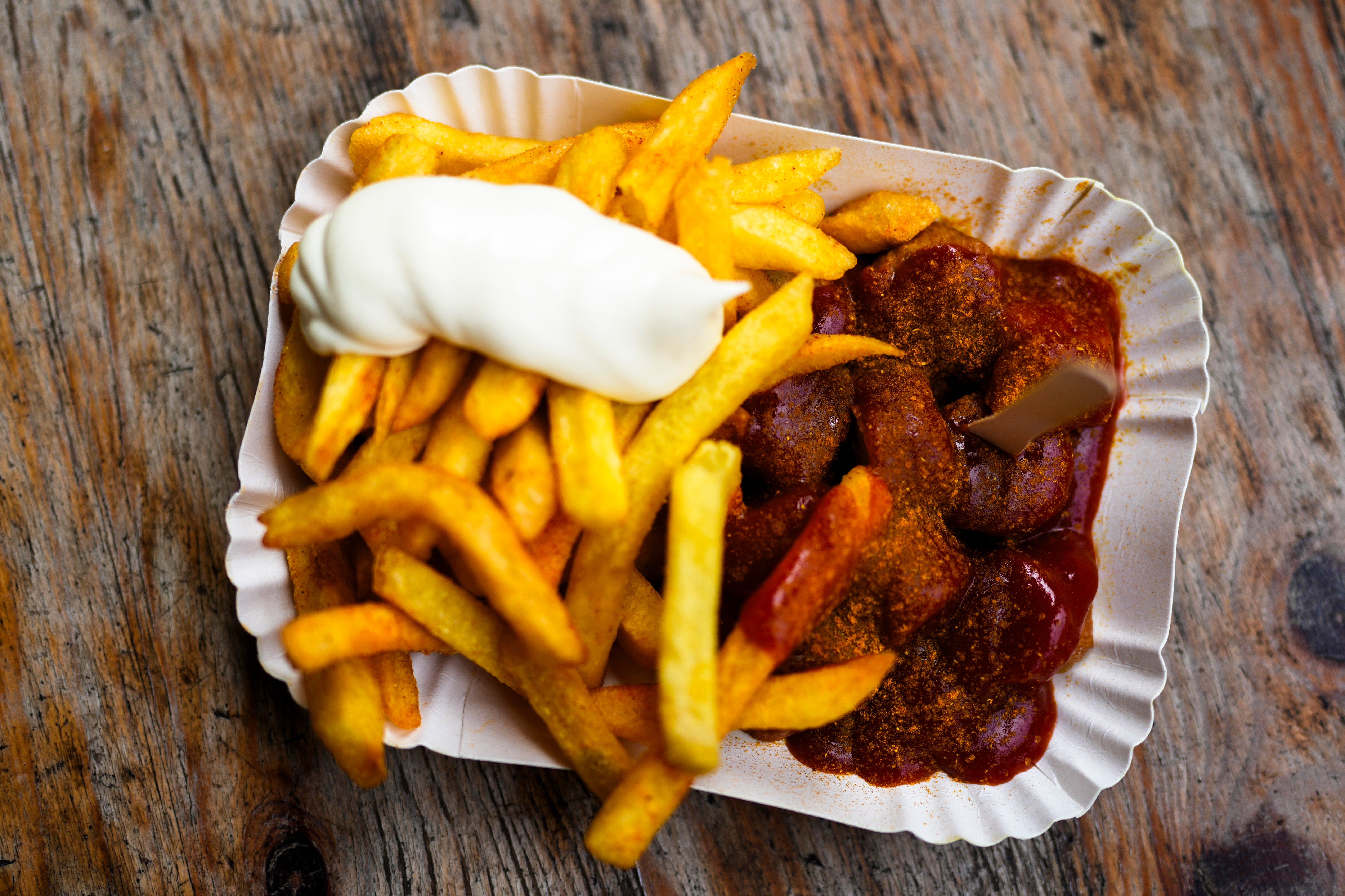 Currywurst, Germany’s sausage with curry sauce, served on a cardboard platter with French fries and mayonnaise
