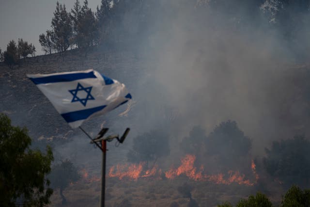 <p>An Israeli flag flutters next to a fire burning in an area near the border with Lebanon, northern Israel in Safed, Wednesday, June 12, 2024</p>