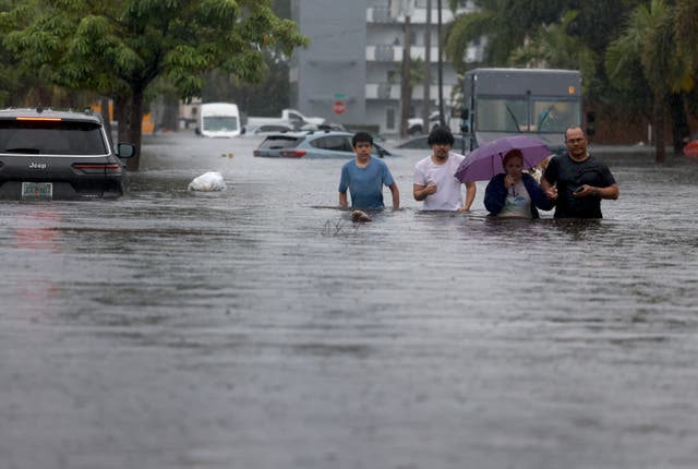 <p> People walk through a flooded street as they evacuate on June 12, 2024, in Hollywood, Florida</p>