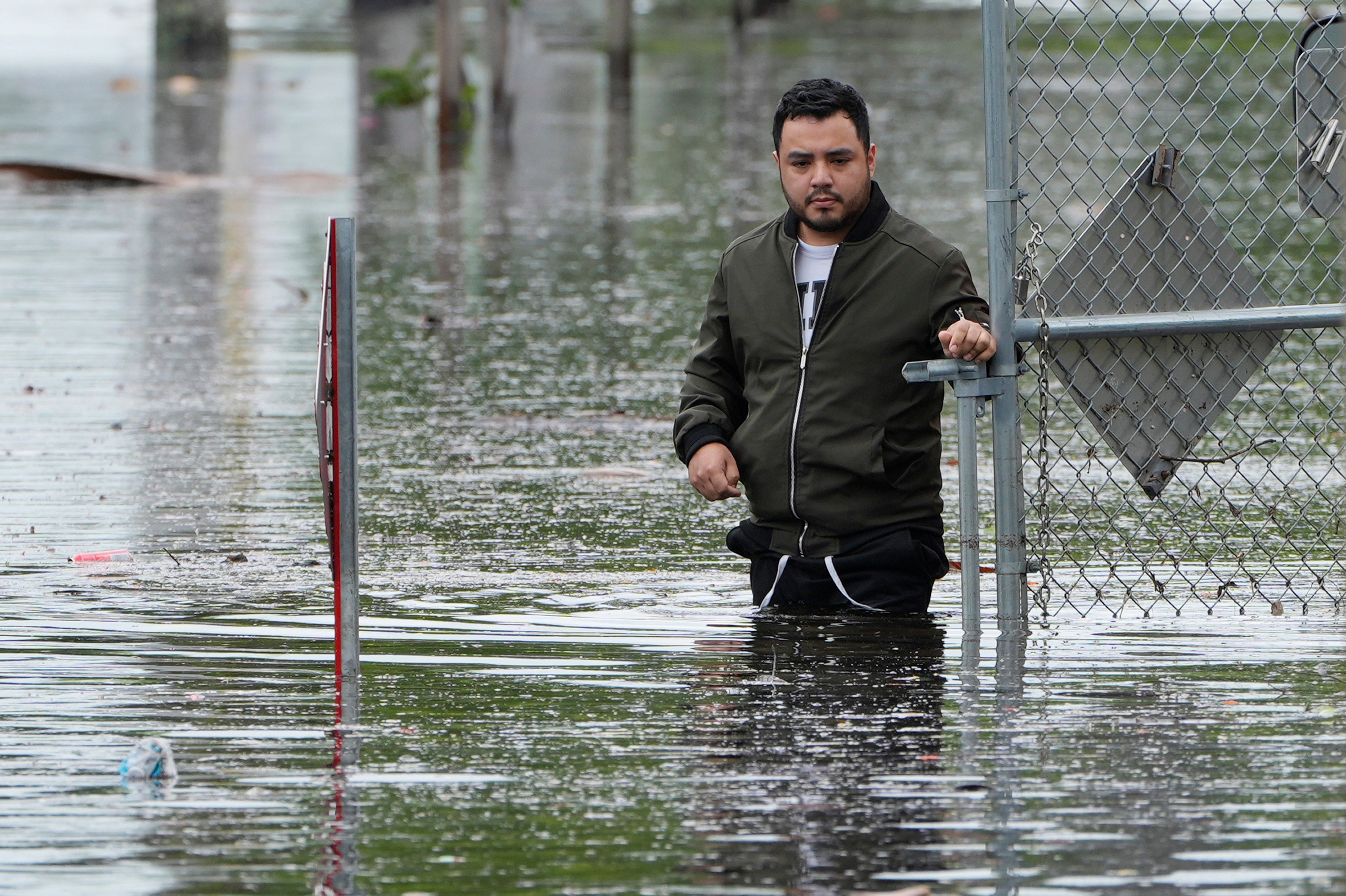 Man stands near the flooded parking lot of his apartment building, Thursday, June 13, 2024, in Hallandale, Florida