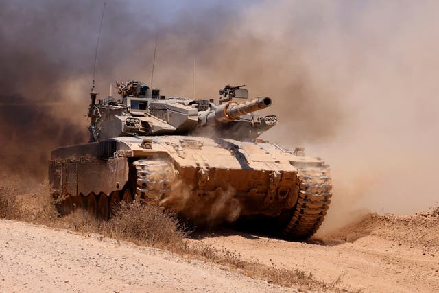 <p>An Israeli army tank rolls along a position in an area of Israel's southern border</p>