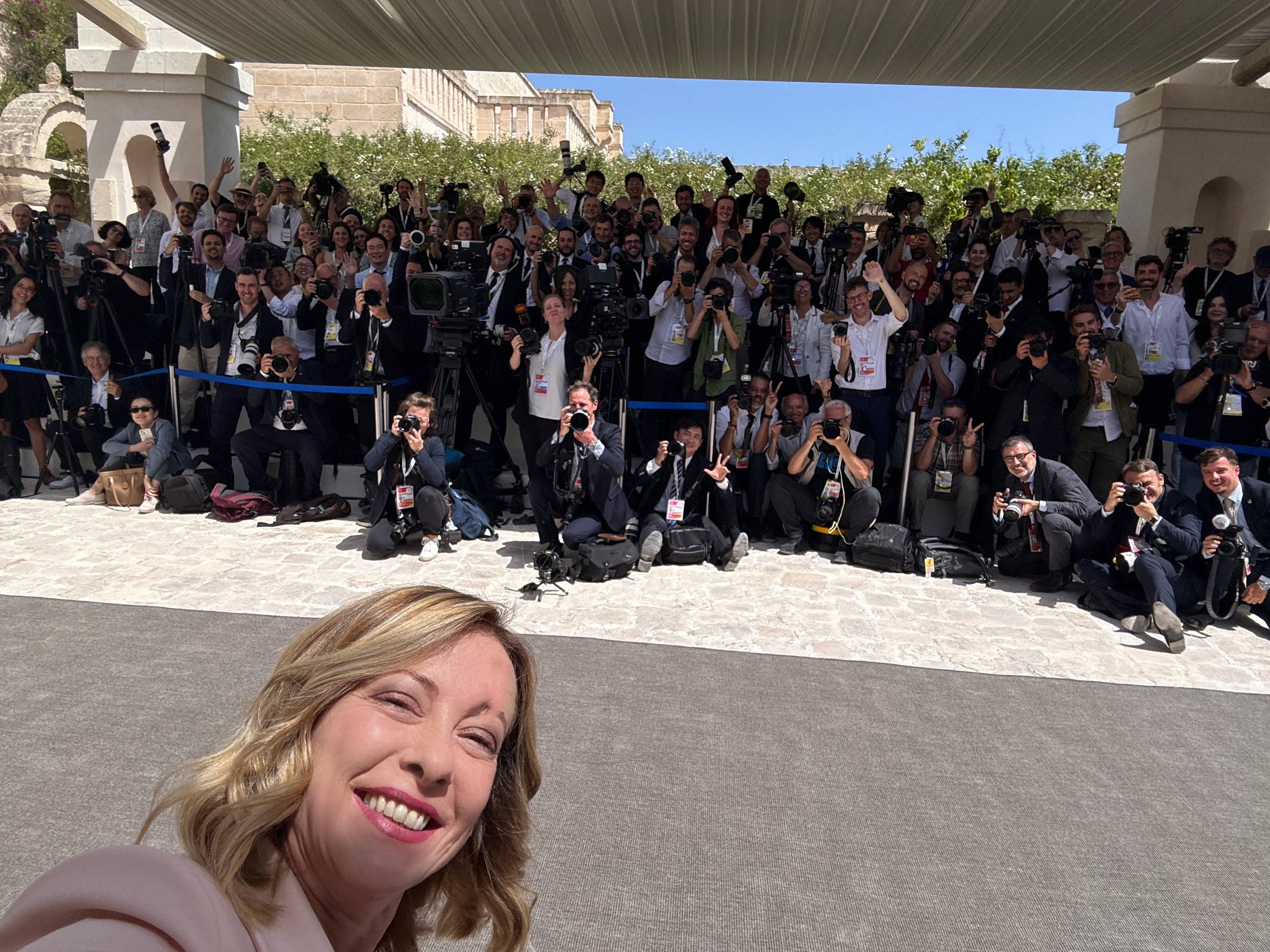 Giorgia Meloni takes a selfie in front of the media while awaiting the arrival of Joe Biden