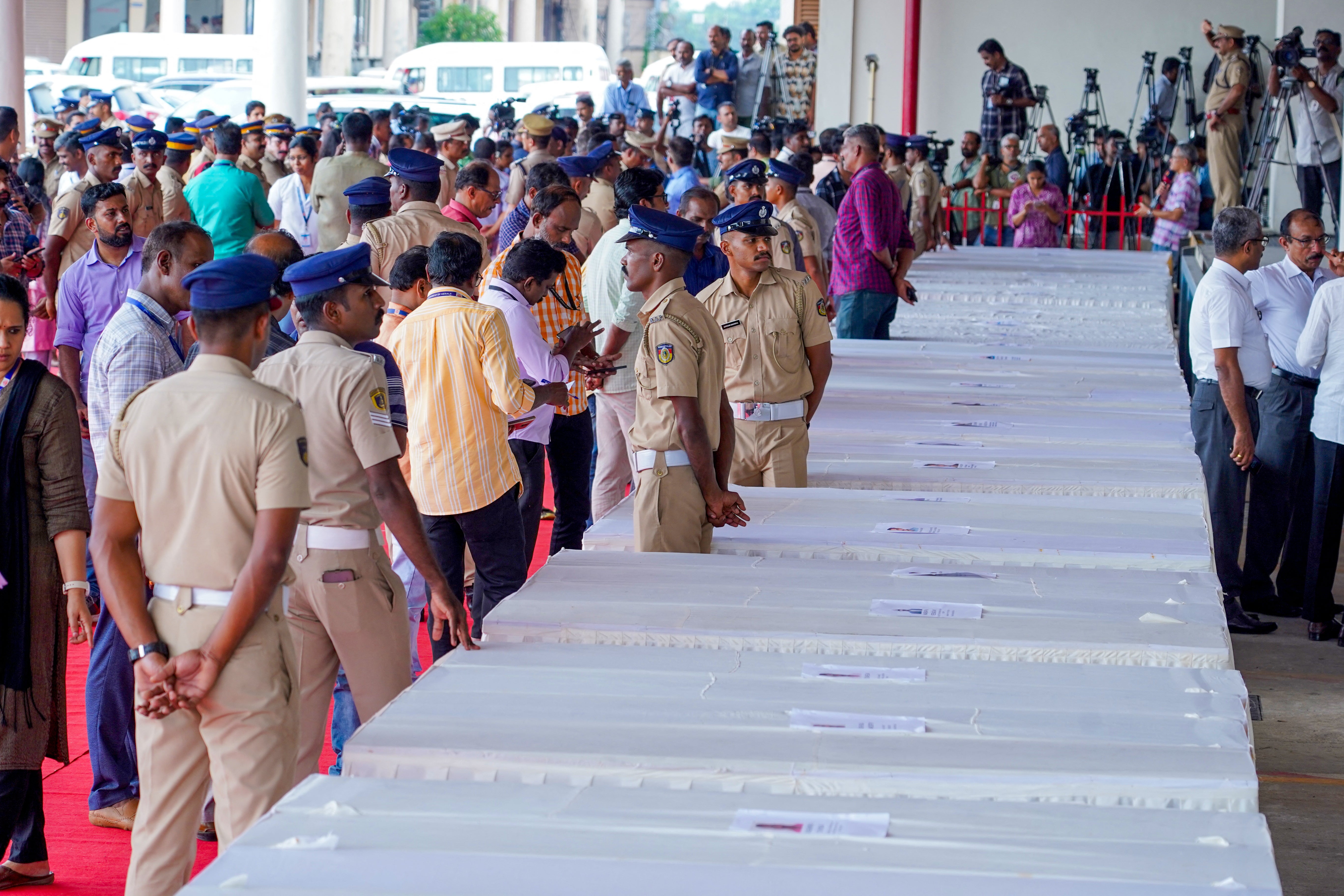 Policemen stand guard as mourning relatives wait for coffins of Indian workers killed in the Kuwait fire to arrive in Kochi