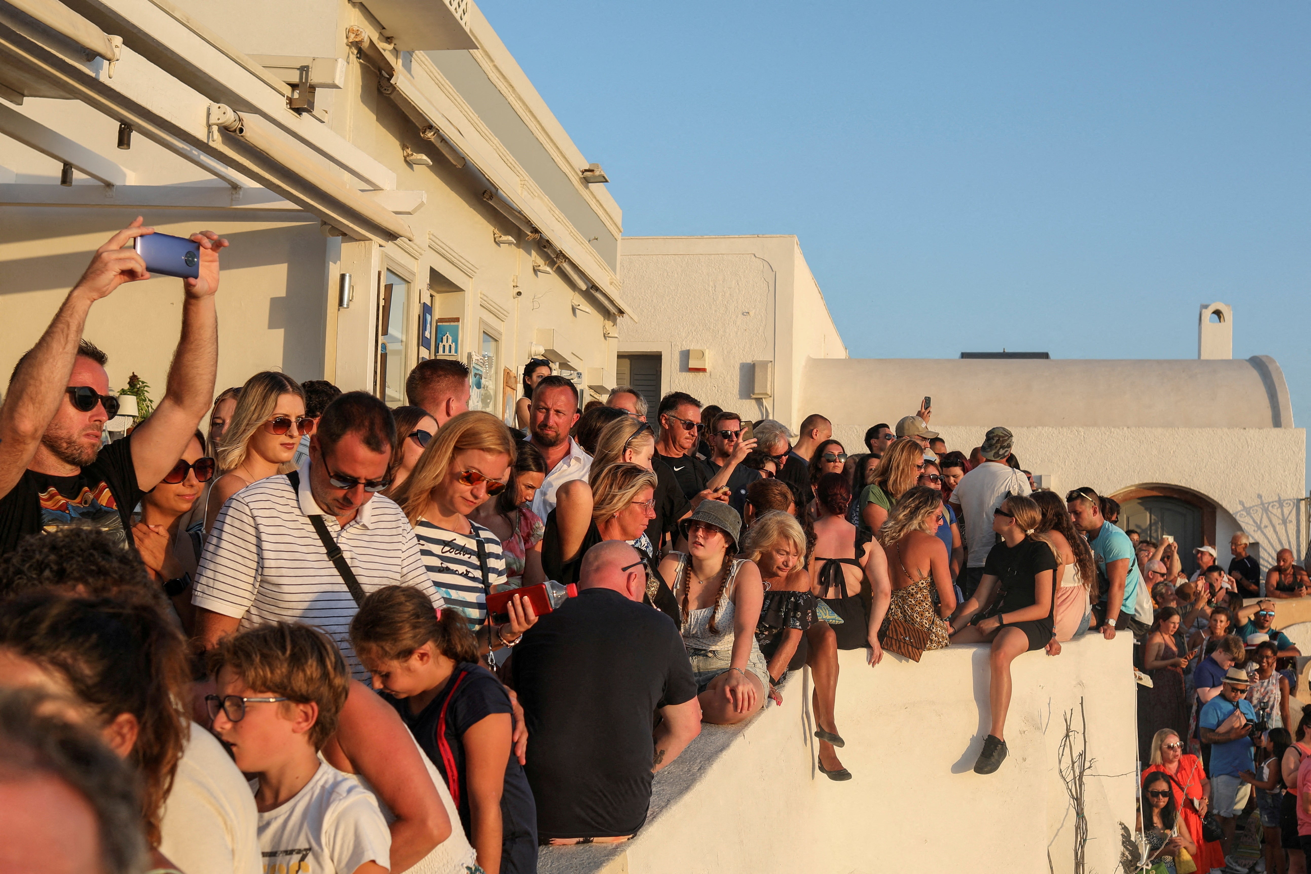 Tourists watch the sunset from the castle of Oia, on the island of Santorini, Greece, August 30, 2022