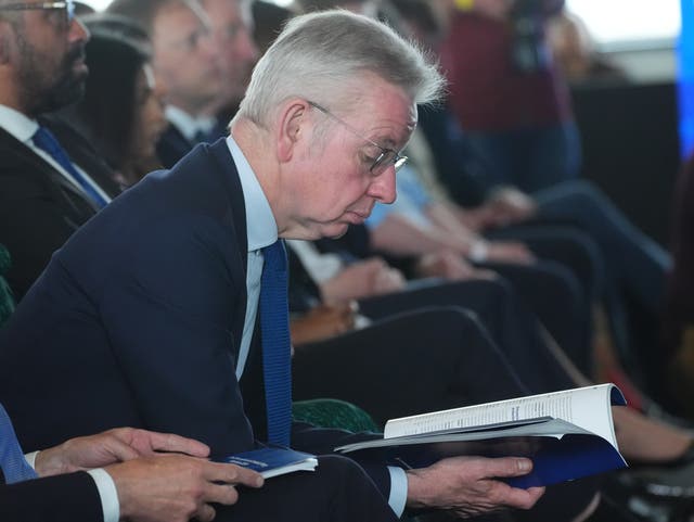<p>Michael Gove searches for a mention of levelling up in the new Tory manifesto (it’s on page 72)</p>