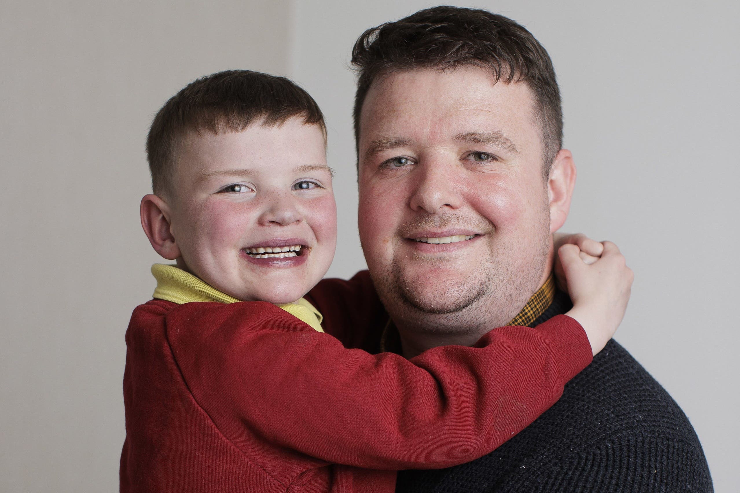 Mairtin Mac Gabhann holding his son Daithi at their family home in west Belfast (Liam McBurney/PA)