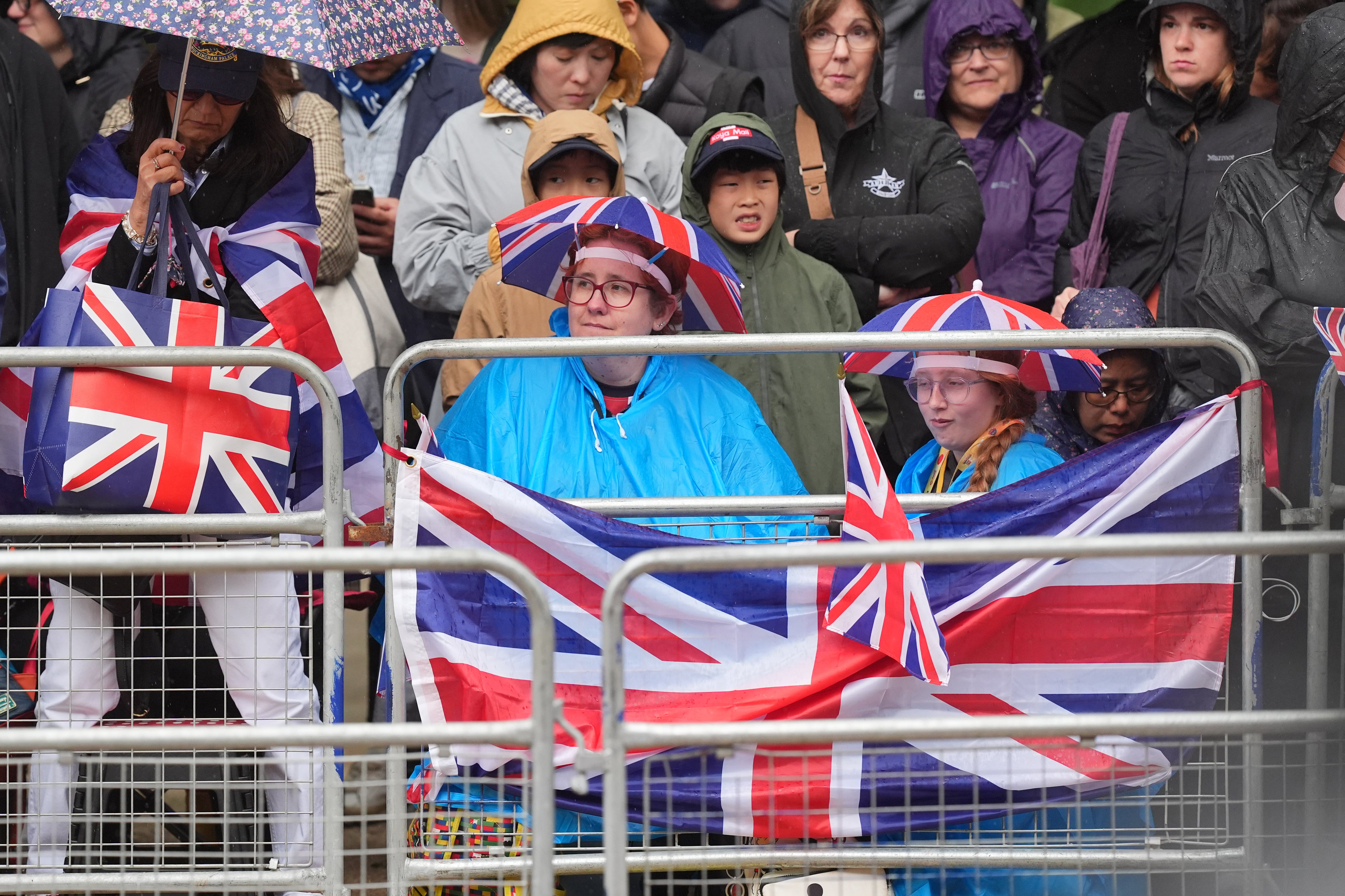 Crowds with umbrellas wait in the rain to see the Royal Family