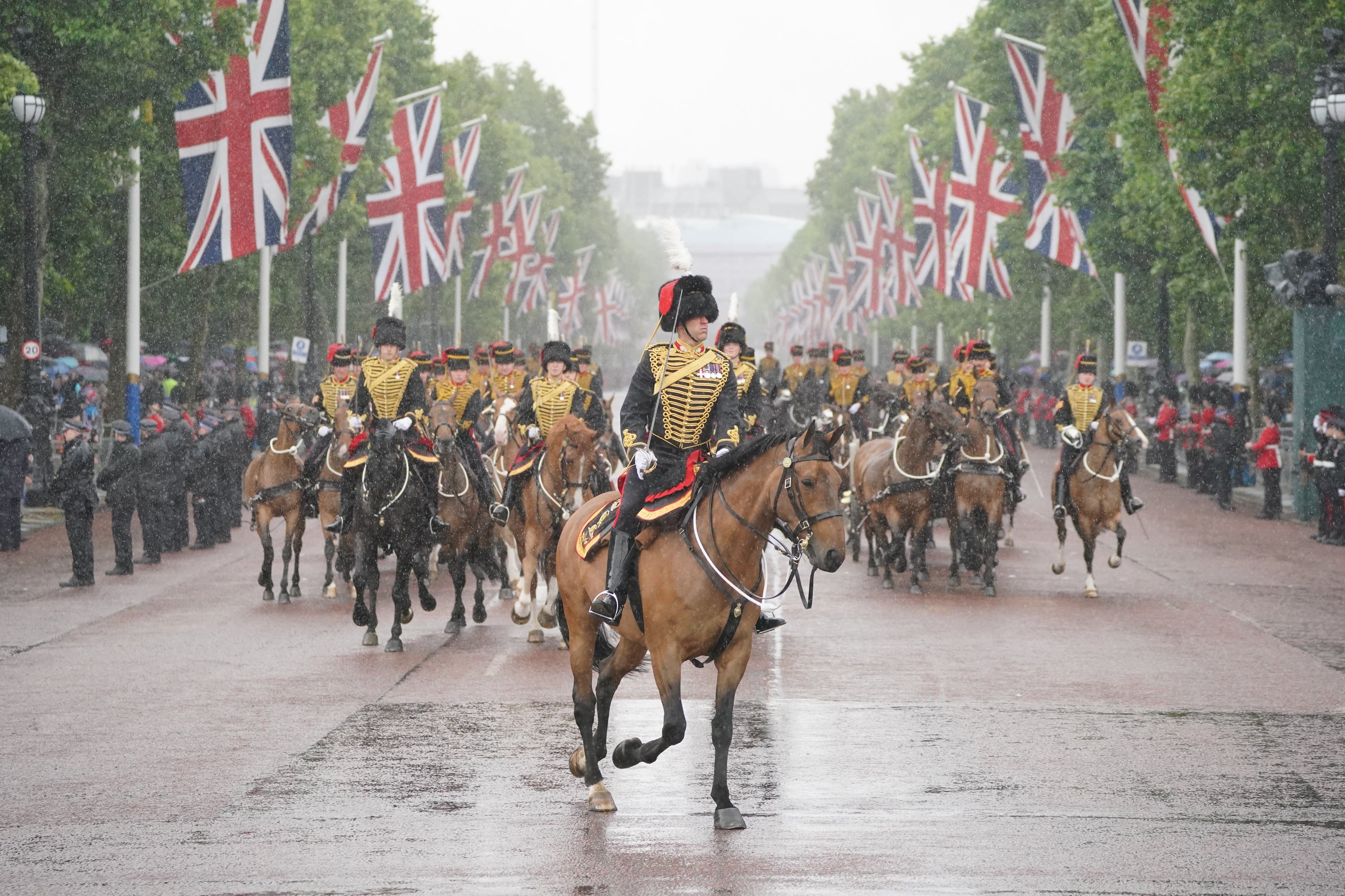 Members of the military ride in heavy rain return from the royal procession