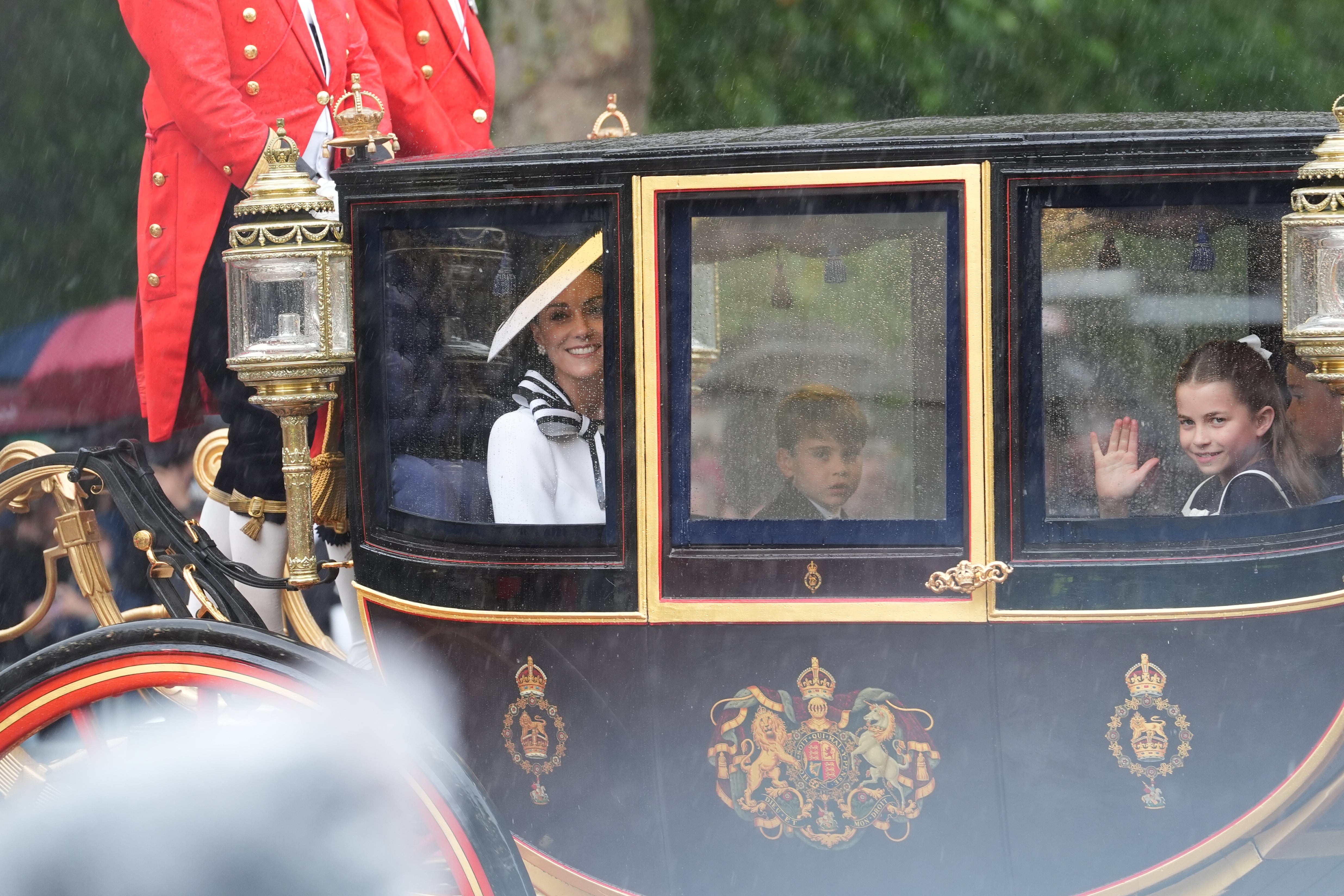 Princess Charlotte waving at the crowds as rain falls on the procession