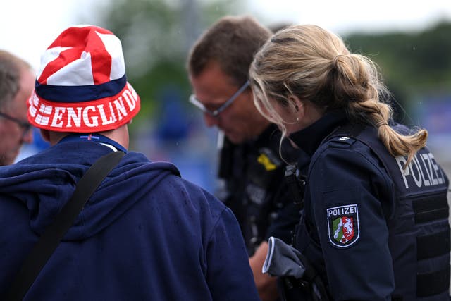 <p>An England football fan speaks with a German police officer before the game against Serbia</p>