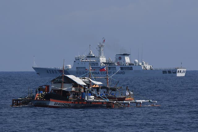 <p>A China Coast Guard ship (R) sailing past a Philippine fishing boat in the disputed South China Sea</p>