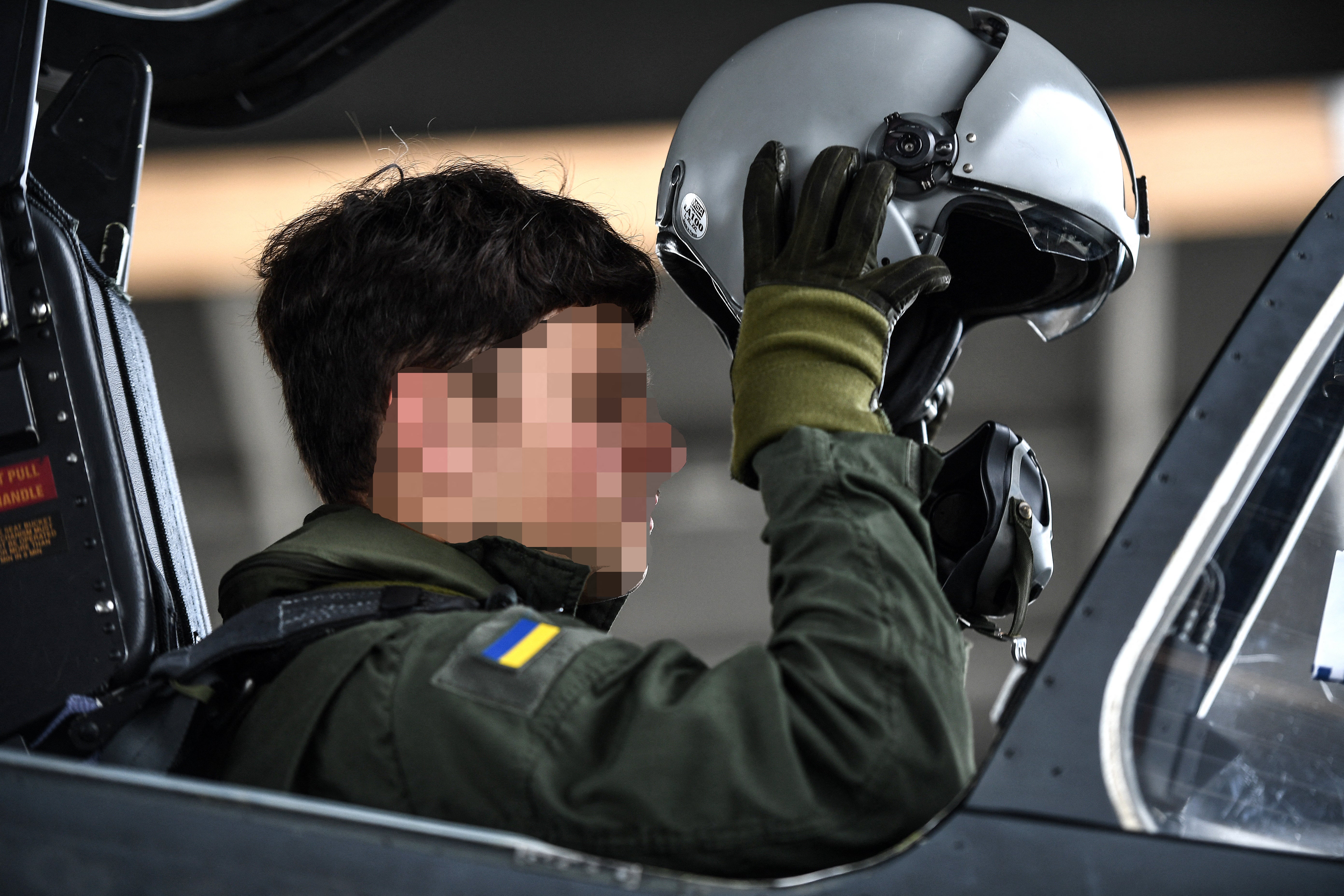 A Ukrainian trainee puts on his helmet ahead of a flight with an unseen French military instructor onboard an Alpha Jet fighter jet, at a French Army air base in south-western France