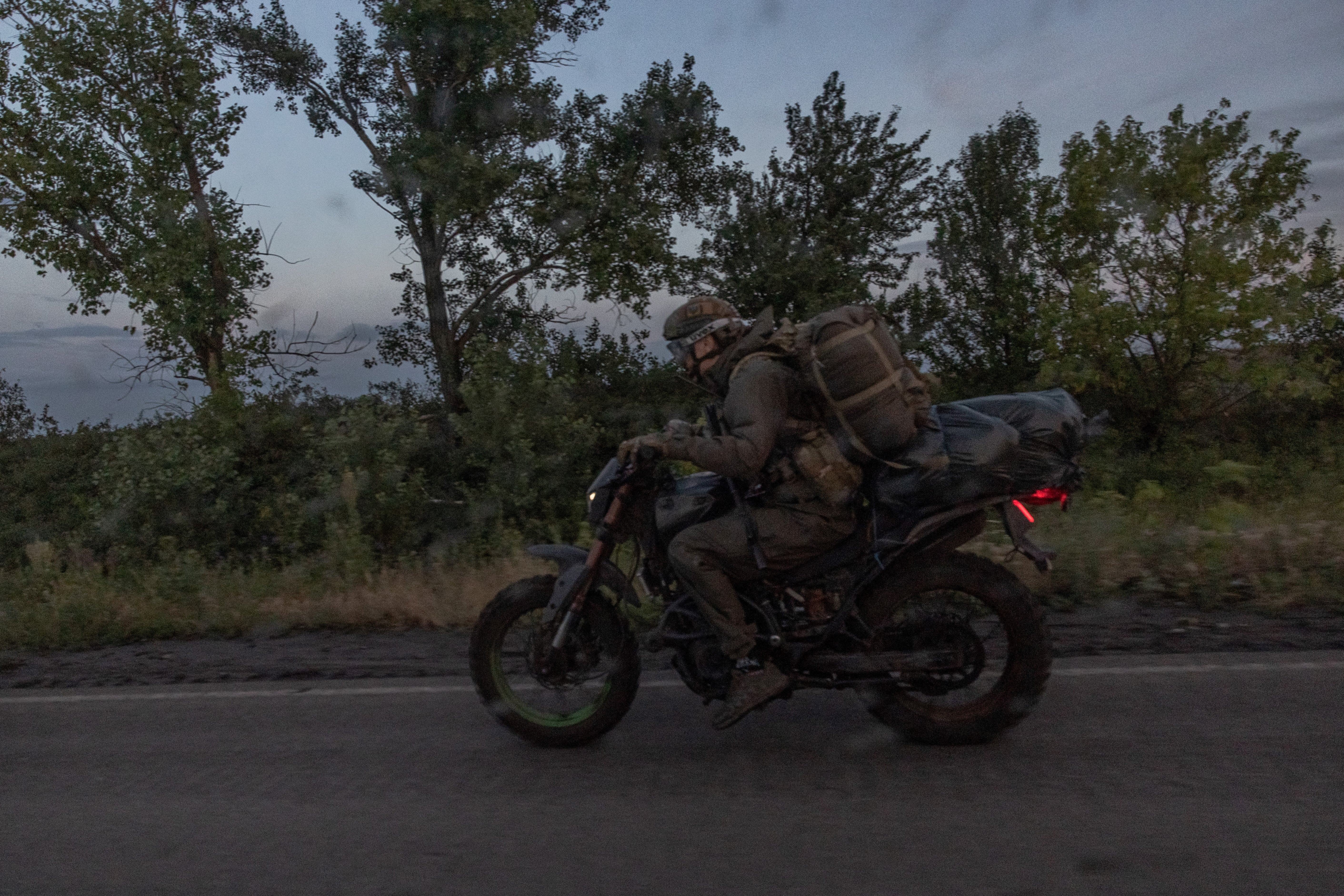 A Ukrainian serviceman rides a motorcycle on a road in the Donetsk region
