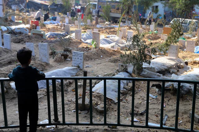 <p>A Palestinian child looks at the graves of people killed in the Israeli bombardment of the Gaza Strip and buried inside the Shifa Hospital grounds in Gaza City</p>