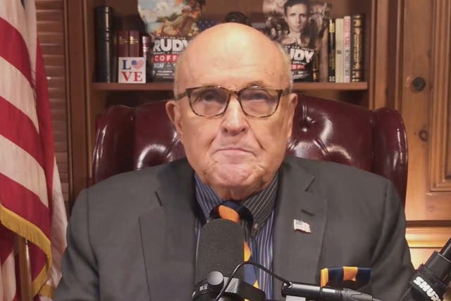 <p>Giuliani sitting in front of his shelf featuring self-branded coffee</p>