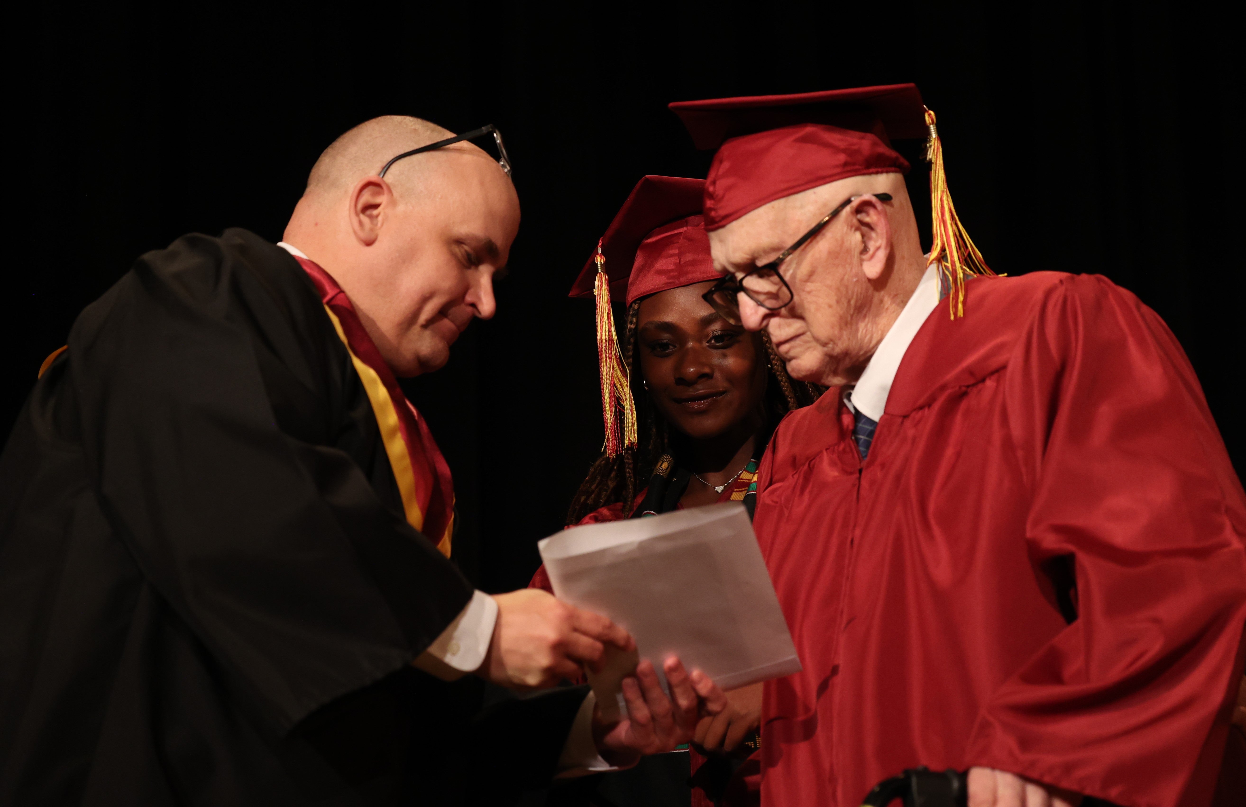 Harlan Olson, 101, accepts his diploma at Denfeld High School this month alongside senior Grace Nonnemacher