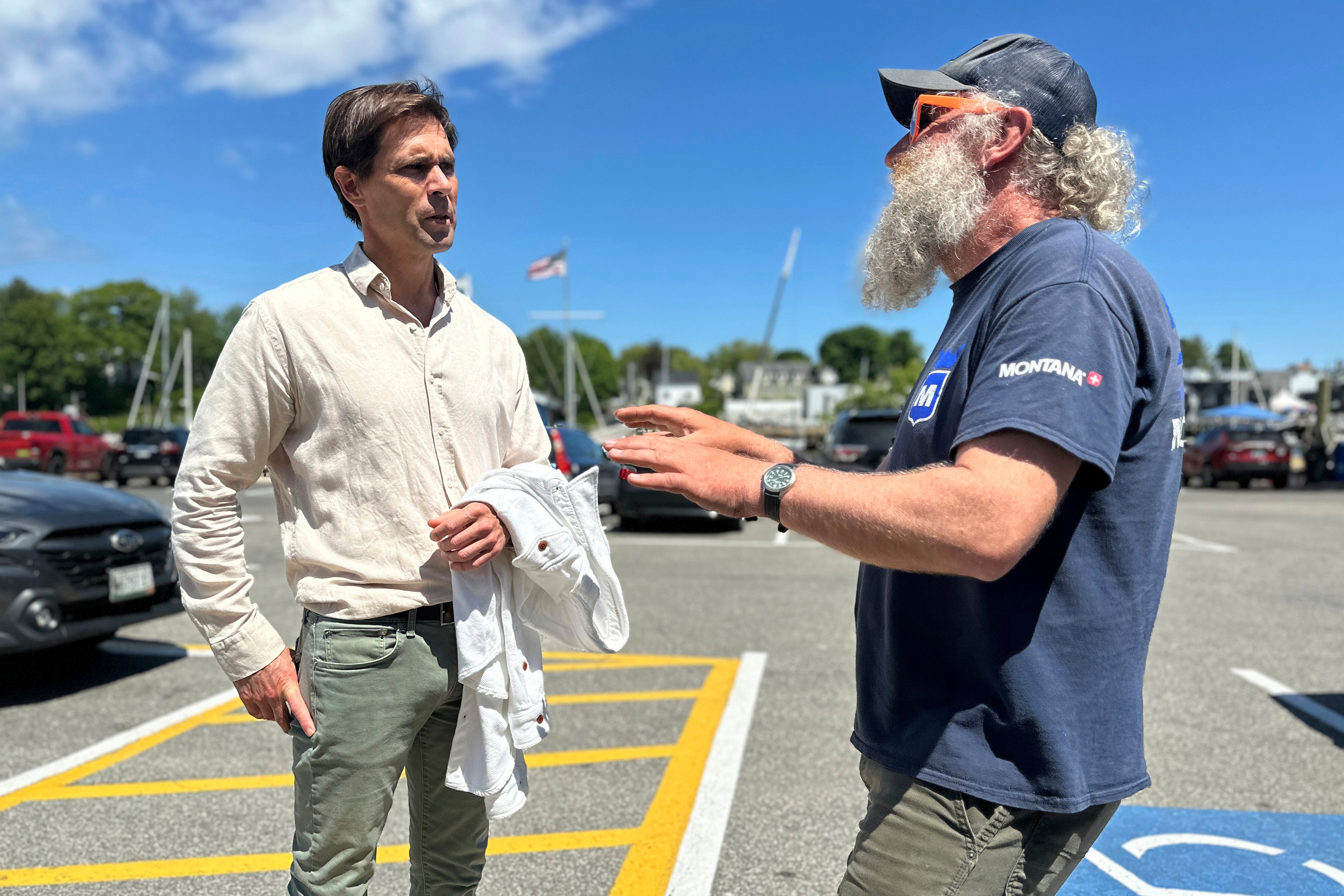 Tom Hedstrom, chair of the Select Board, speaks with schooner captain Aaron Lincoln during a visit to the harbor