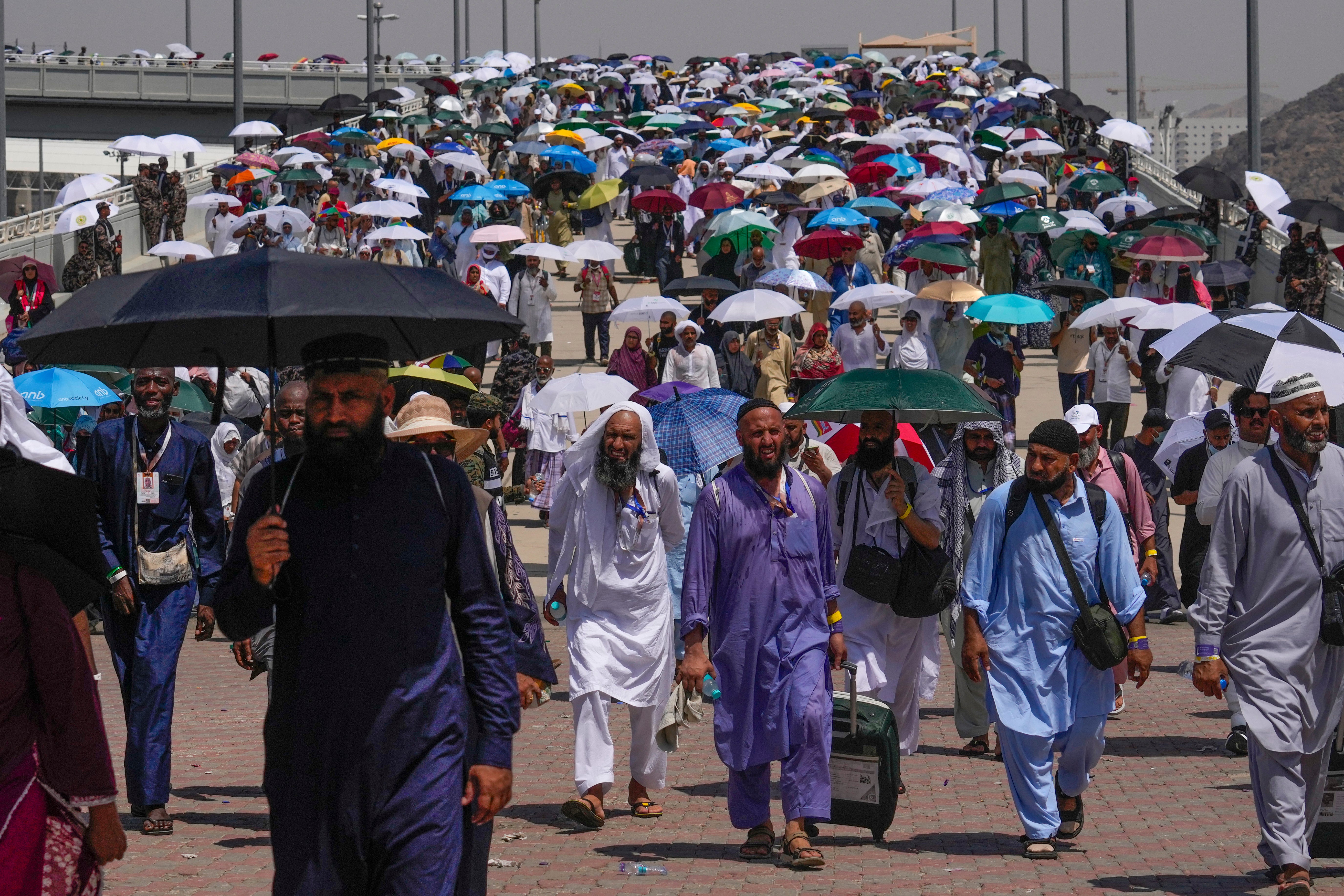 Pilgrims use umbrellas to shield themselves from the sun