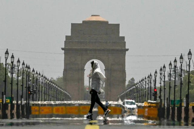 <p>A man wears a scarf as he walks past the India Gate on a hot summer day in New Delhi</p>