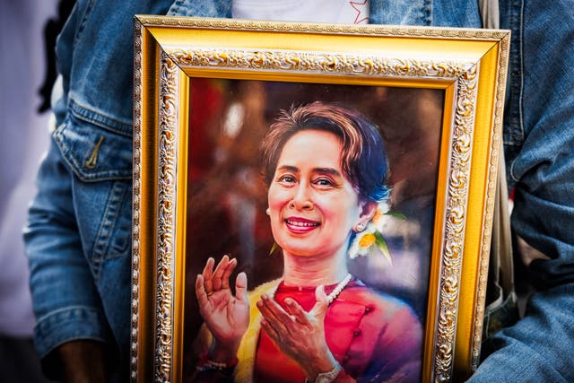 <p>Myanmar people hold up photos of Democratic Leader, Aung San Suu Kyi, during a gathering at the United Nations in Bangkok, Thailand</p>