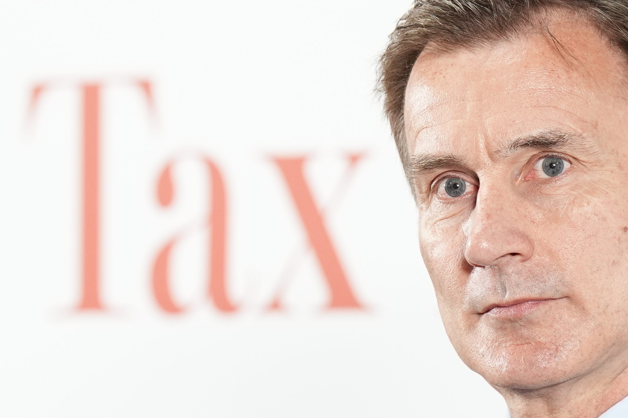Chancellor Jeremy Hunt in front of a white background with the word ‘Tax’ on it (Aaron Chown/PA)