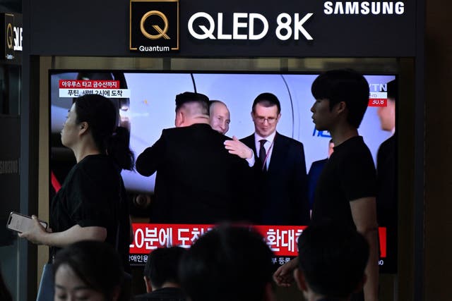 <p>People in Seoul walk past a television showing a news broadcast with footage of North Korea’s leader Kim Jong Un greeting Vladimir Putin in Pyongyang </p>