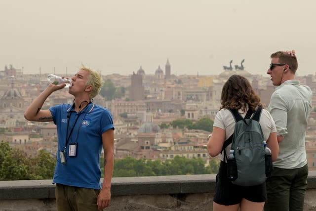 <p>A man drinks water as a haze of heat is seen above Rome with temperatures expected to rise to 39 degrees today on June 20, 2024</p>