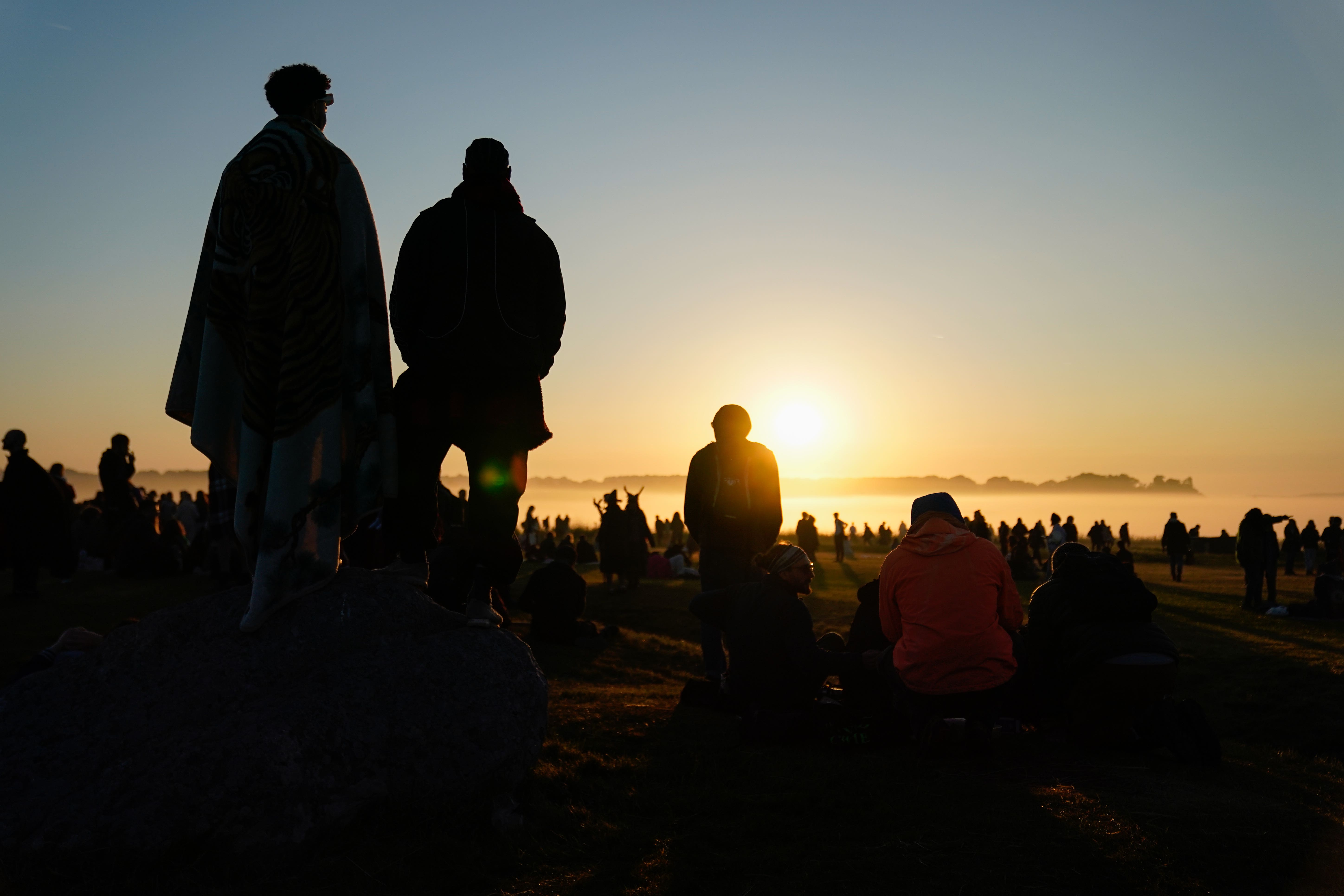 People watch the sun rise as they take part in the summer solstice at Stonehenge in Wiltshire (Andrew Matthews/PA)