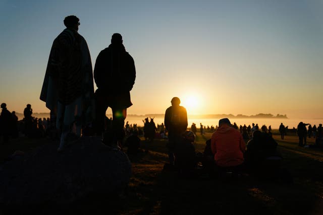 <p>People watch the sun rise as they take part in the summer solstice at Stonehenge in Wiltshire (Andrew Matthews/PA)</p>