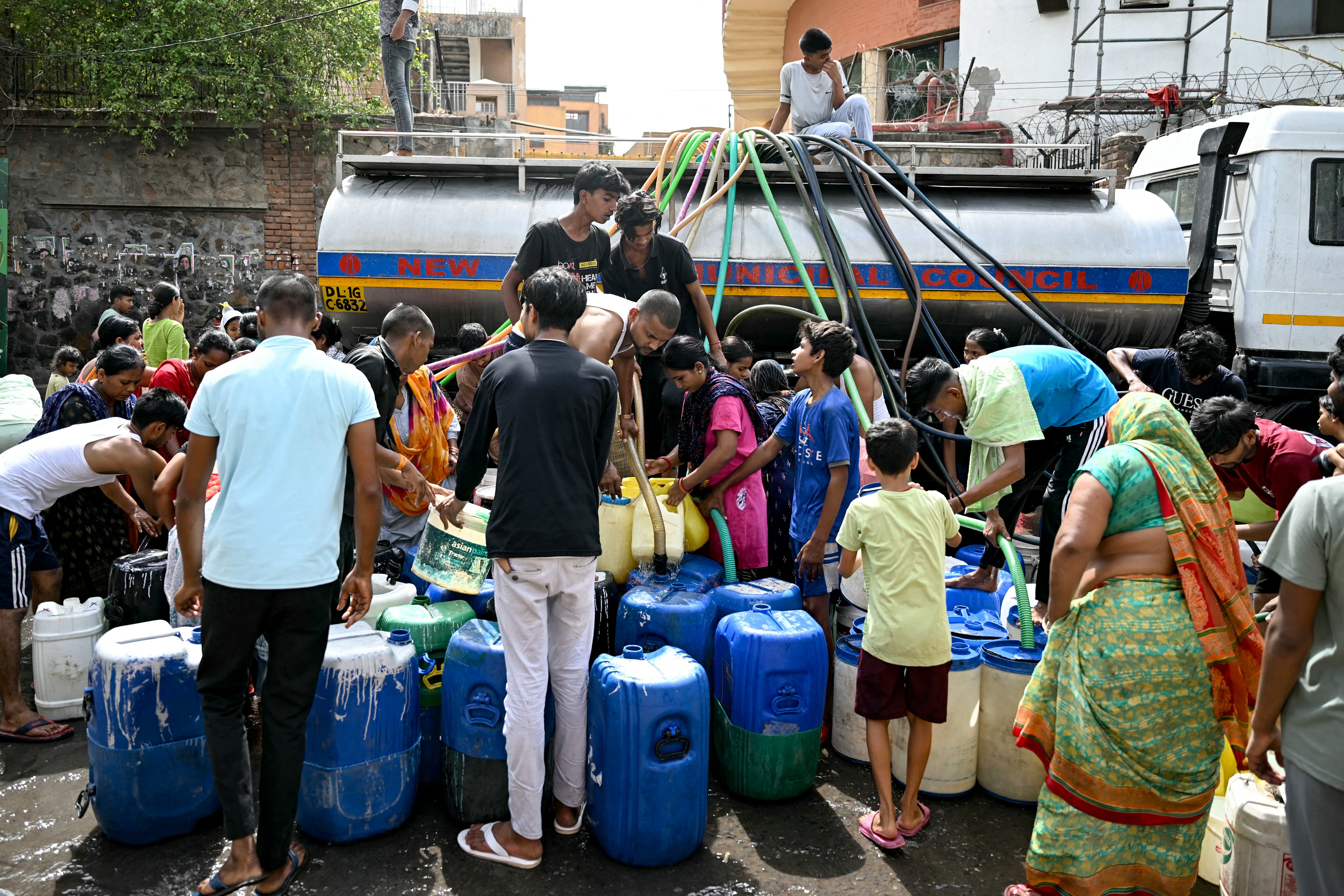 Residents fill their containers with water supplied by a municipal tanker in Delhi, India