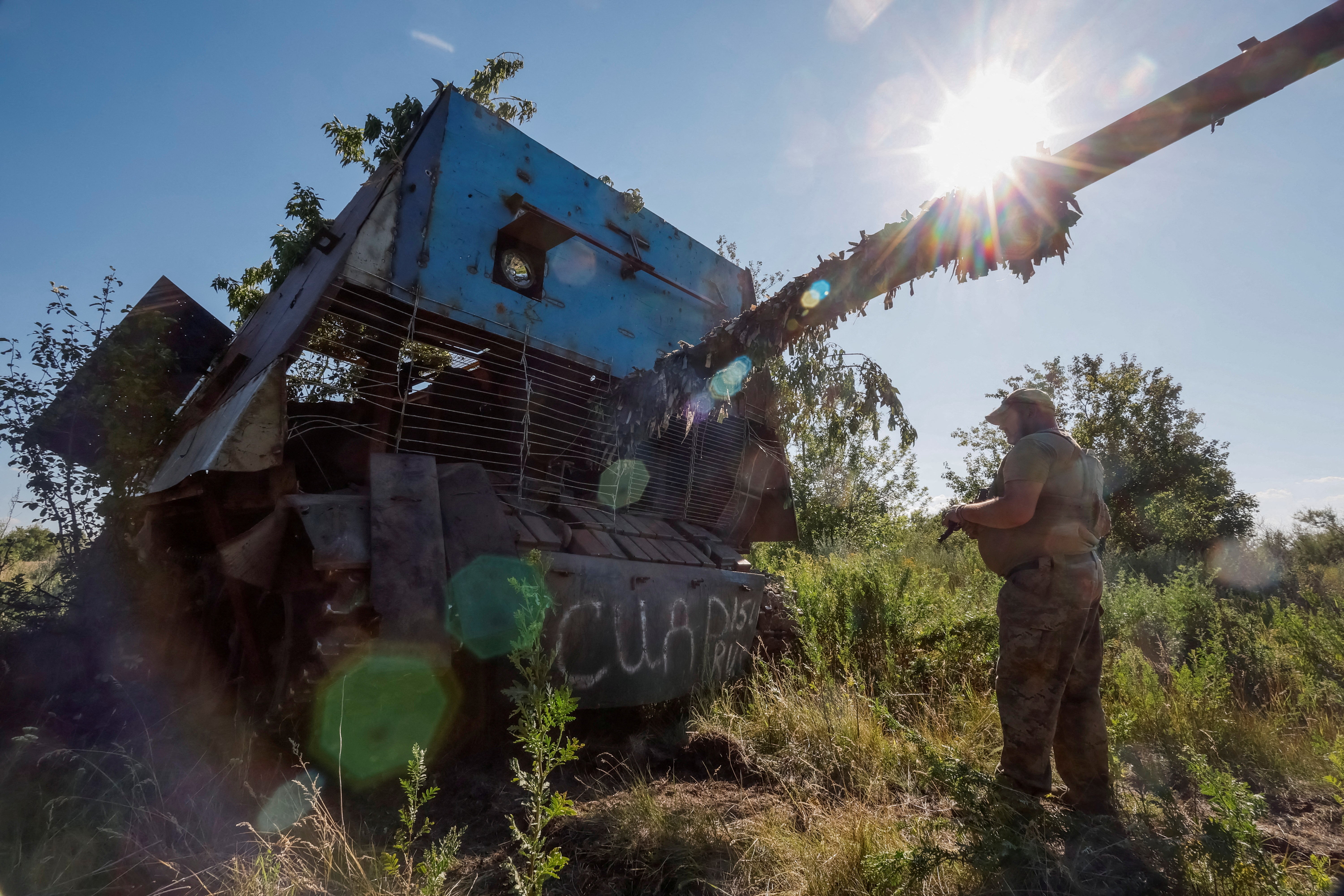 A Ukrainian serviceman of the 22nd Separate Mechanised Brigade stands next to a Russian T-62 Soviet main battle tank crafted with anti-drone protection that was recently captured by his unit at an undisclosed location in Donetsk region,