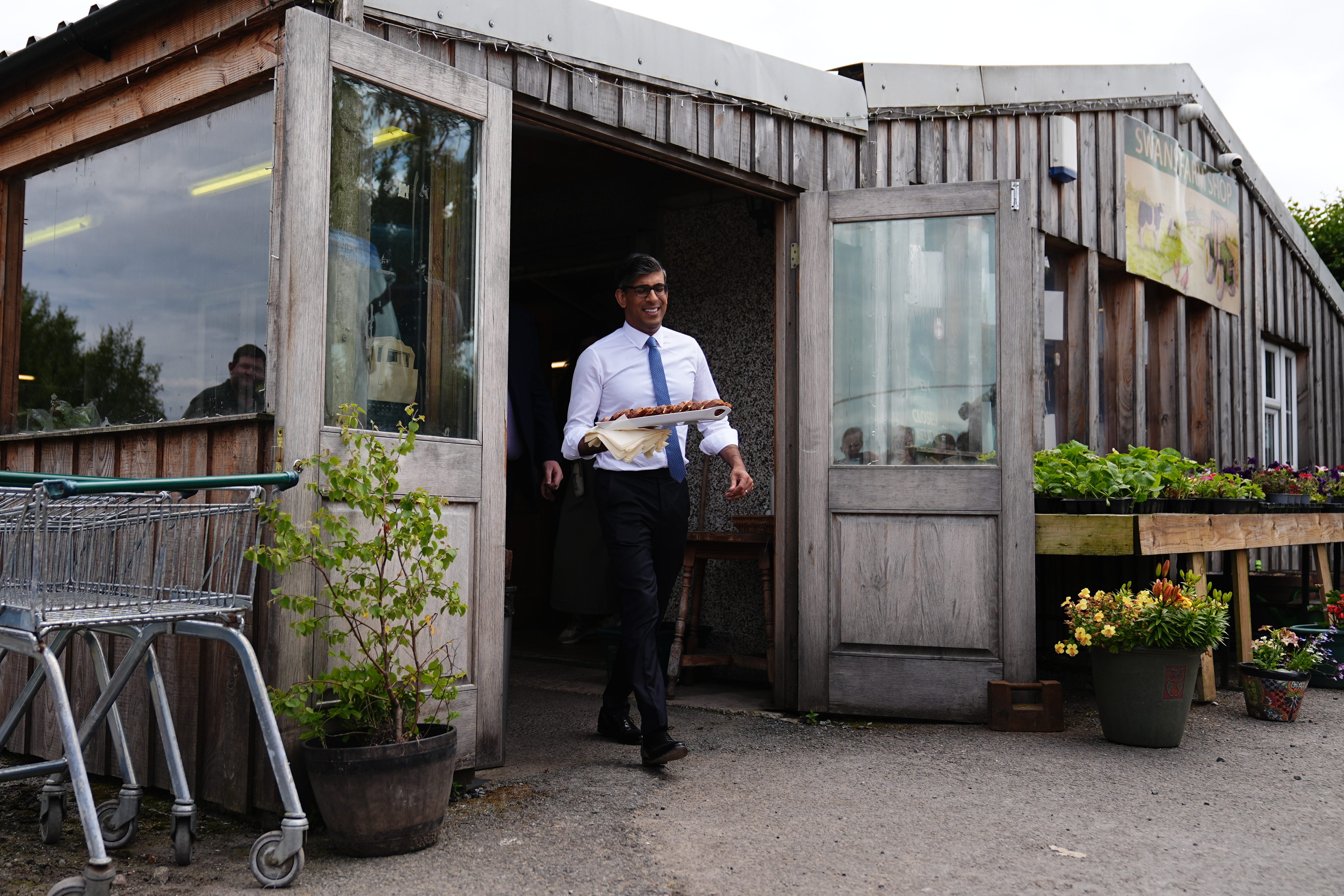 Rishi Sunak handed out Bara Brith cake to the media during a visit to a farm shop in Mold on Friday (Aaron Chown/PA)