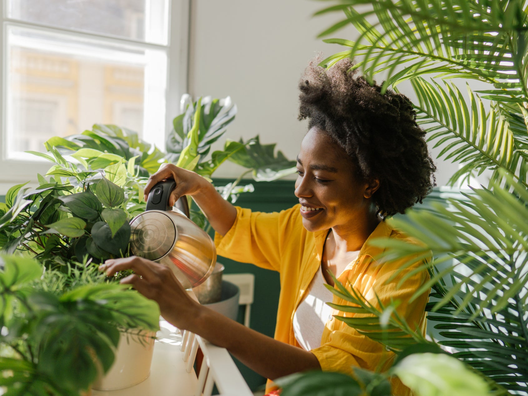 Photo of a young woman, taking care of her houseplants (Getty Images)