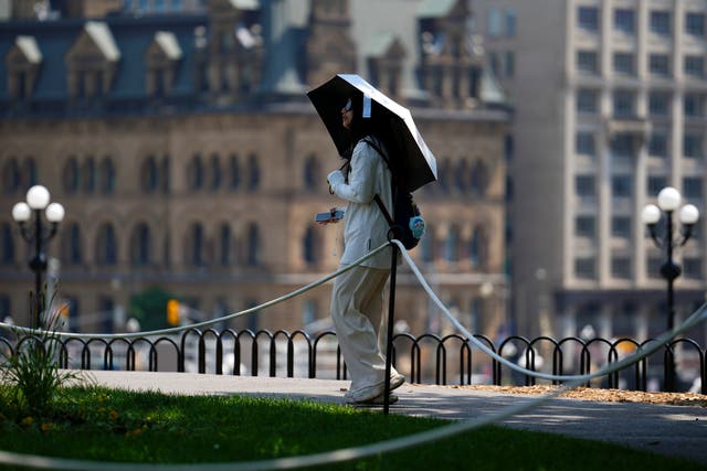 A tourist carries an umbrella as they visit Parliament Hill in Ottawa, Ontario, on Tuesday, June 18, 2024, as temperatures hit 32 Celsius in what meteorologists are calling a heat dome