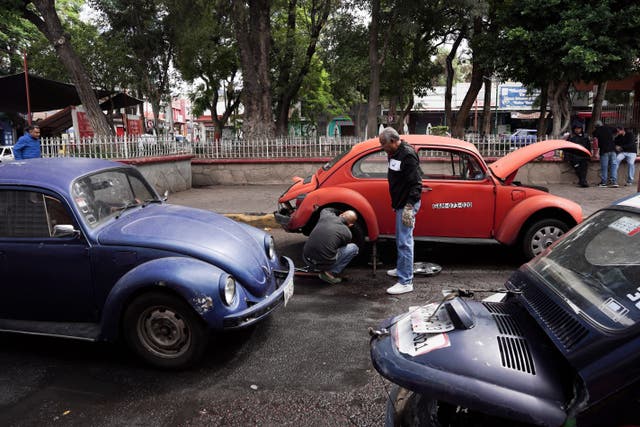 <p>Volkswagen Beetle taxi drivers change a flat tire in the Cuautepec neighborhood of Mexico City, Friday, June 21, 2024</p>