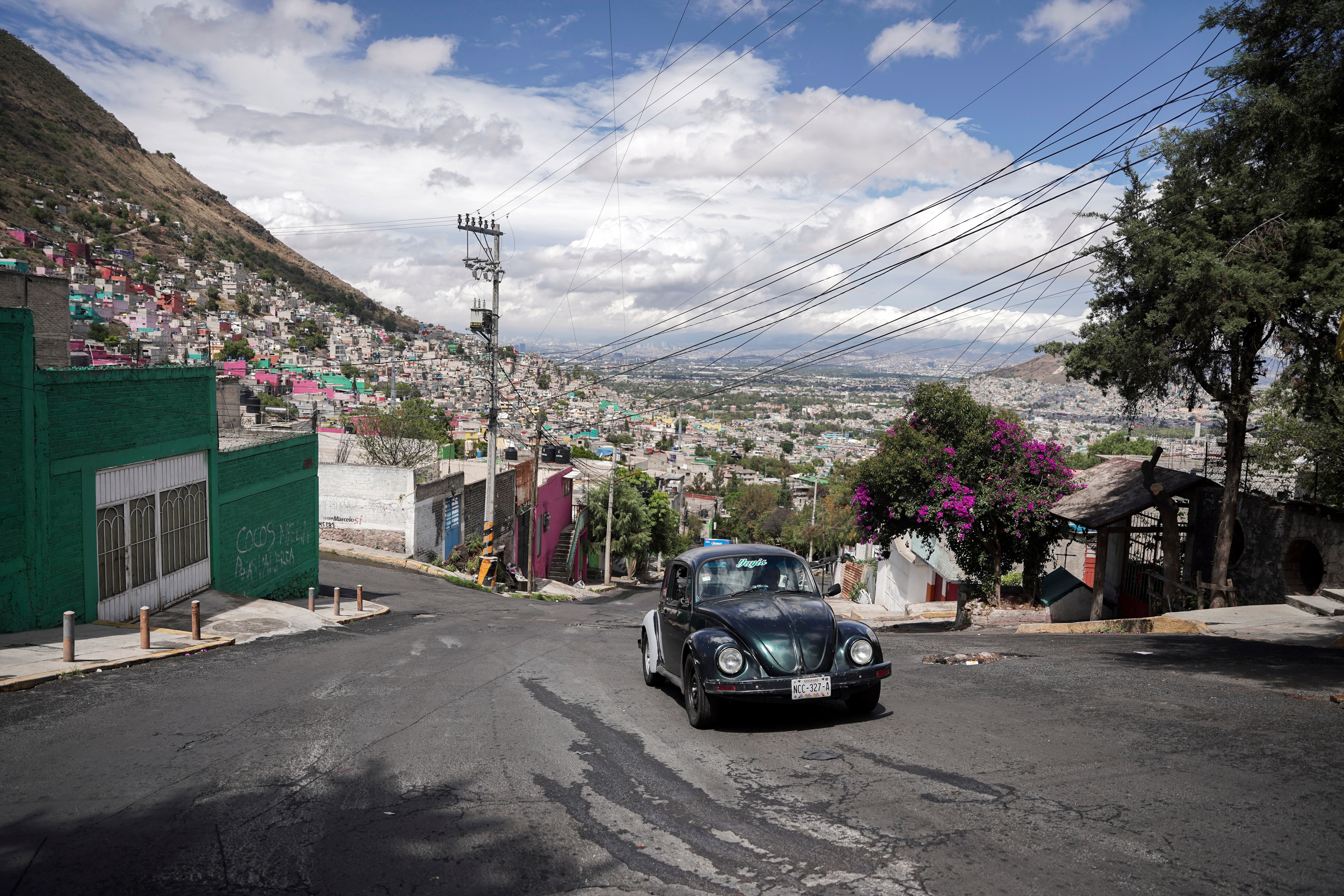 Janette Navarro drives her 1996 Volkswagen Beetle up a steep hill in the Cuautepec neighborhood of Mexico City