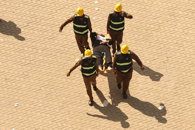 <p>Rescuers carry away a man, affected by the scorching heat, on a stretcher as Muslim pilgrims arrive to perform the symbolic 'stoning of the devil' ritual as part of the hajj pilgrimage</p>