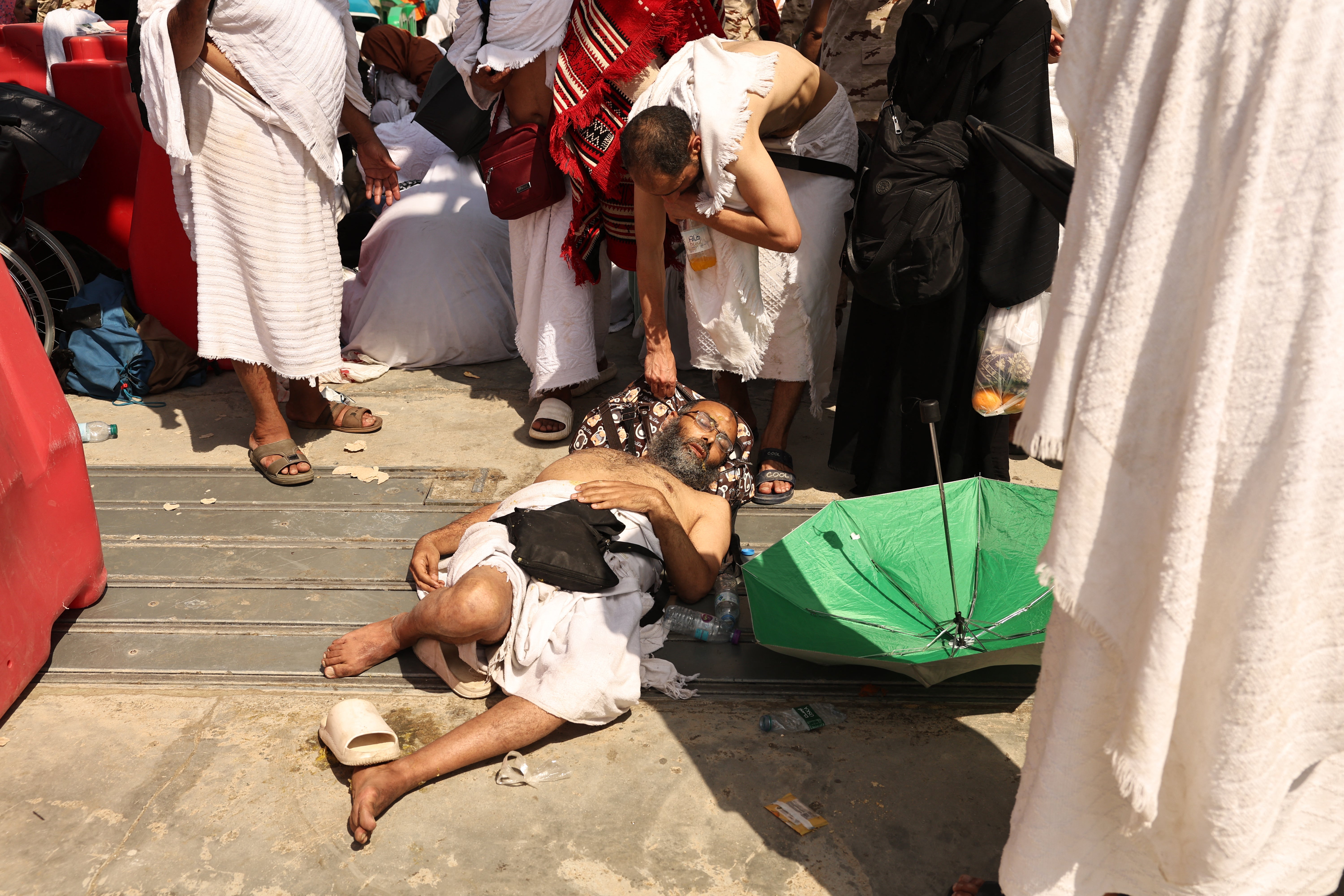 A man, affected by the scorching heat, is helped by another Muslim pilgrim as they arrive to perform the symbolic 'stoning of the devil' ritual during the annual hajj pilgrimage in Mina
