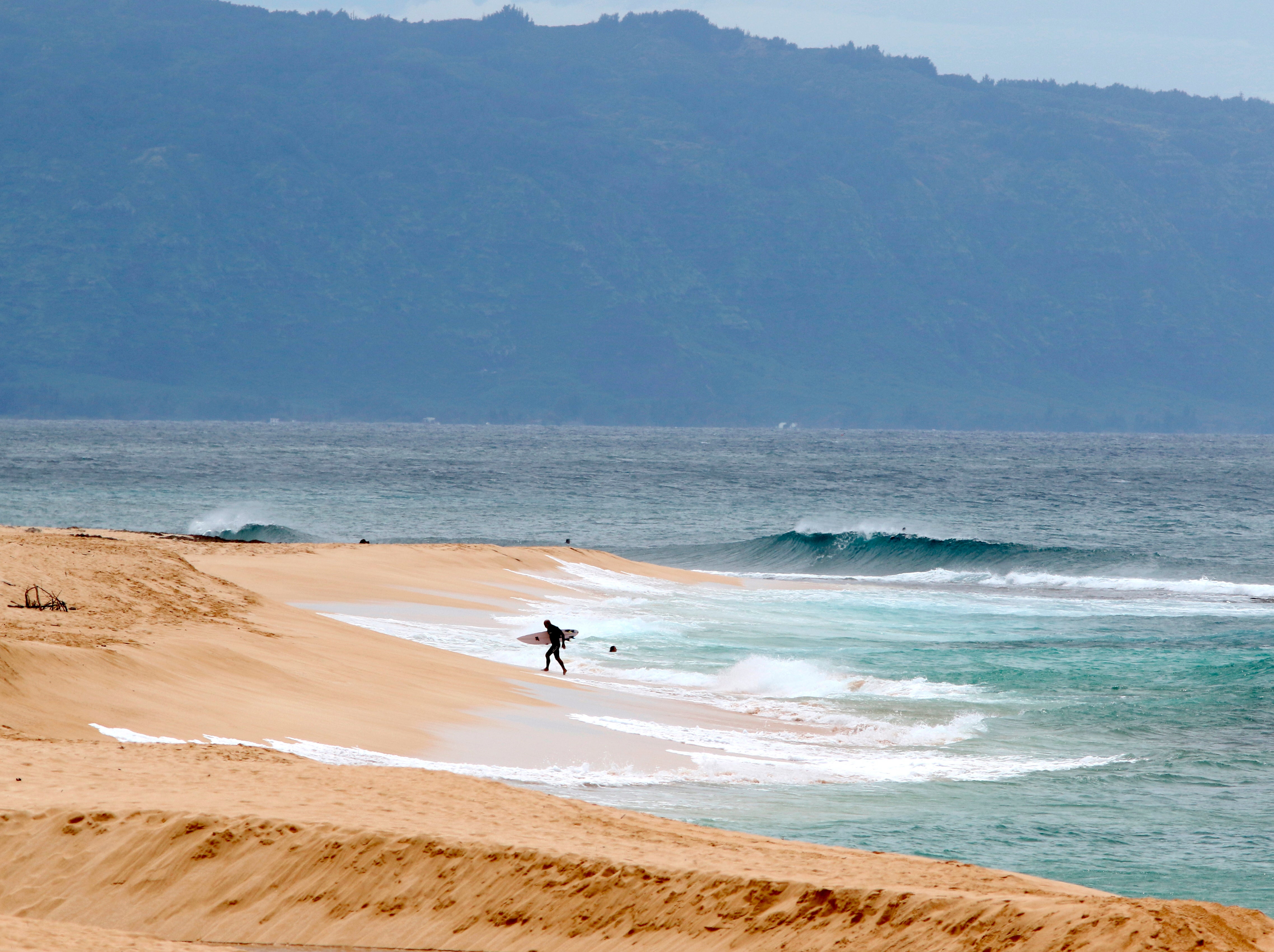 Stock image of a surfer walking out of the ocean on Oahu's North Shore near Haleiwa