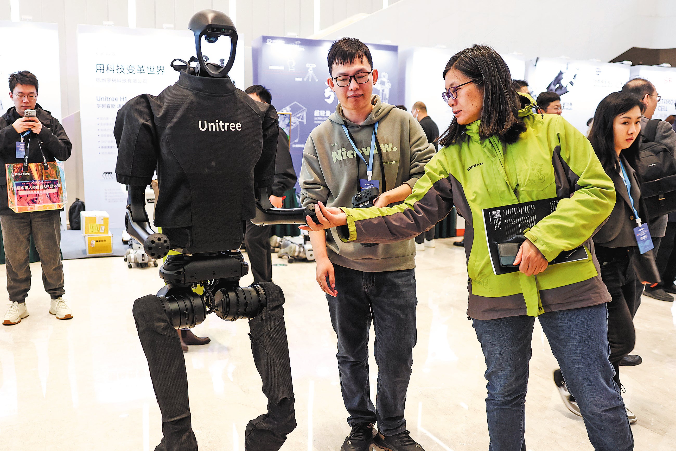 Visitors check out a humanoid robot of Chinese tech startup Unitree Robotics during an expo in Beijing in April