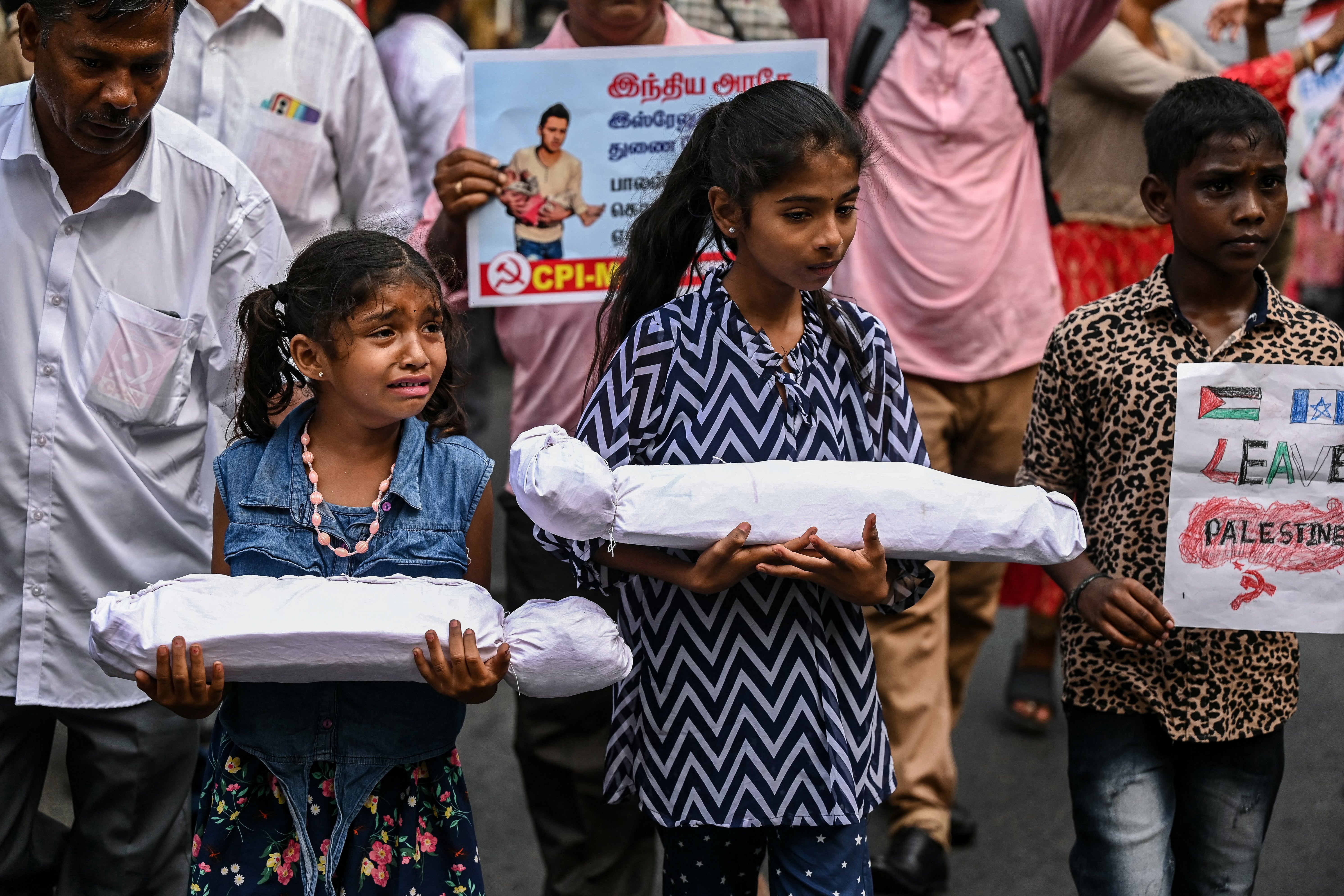 A girl cries as children carrying dummy bodies take part in a demonstration to express their solidarity with the Palestinians, in Chennai