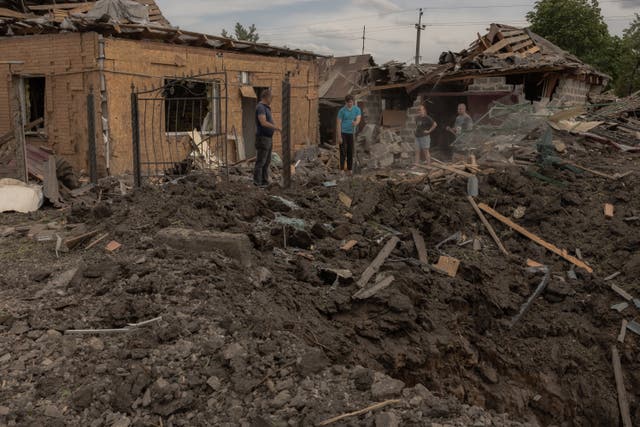 <p>Residents clean debris next to heavily damaged houses following shelling in Pokrovsk, eastern Donetsk region</p>