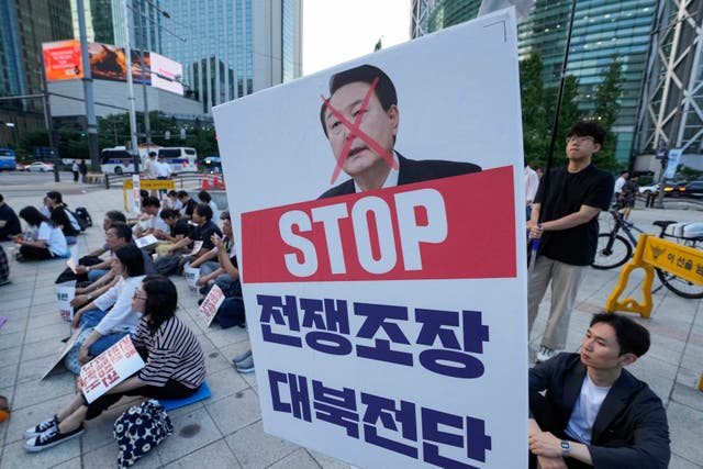 <p>South Korean protesters carry a defaced image of president Yoon Suk Yeol during a rally demanding an end to military exercises and propaganda campaigns amid rising tensions with North Korea, in Seoul on 24 June </p>