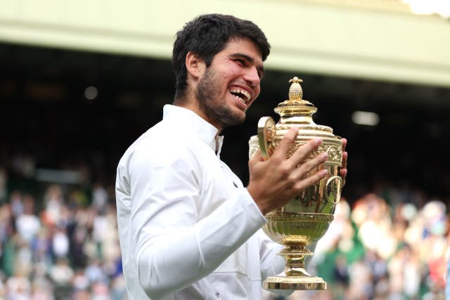 Carlos Alcaraz smiles while holding the Wimbledon trophy (Steven Paston/PA)
