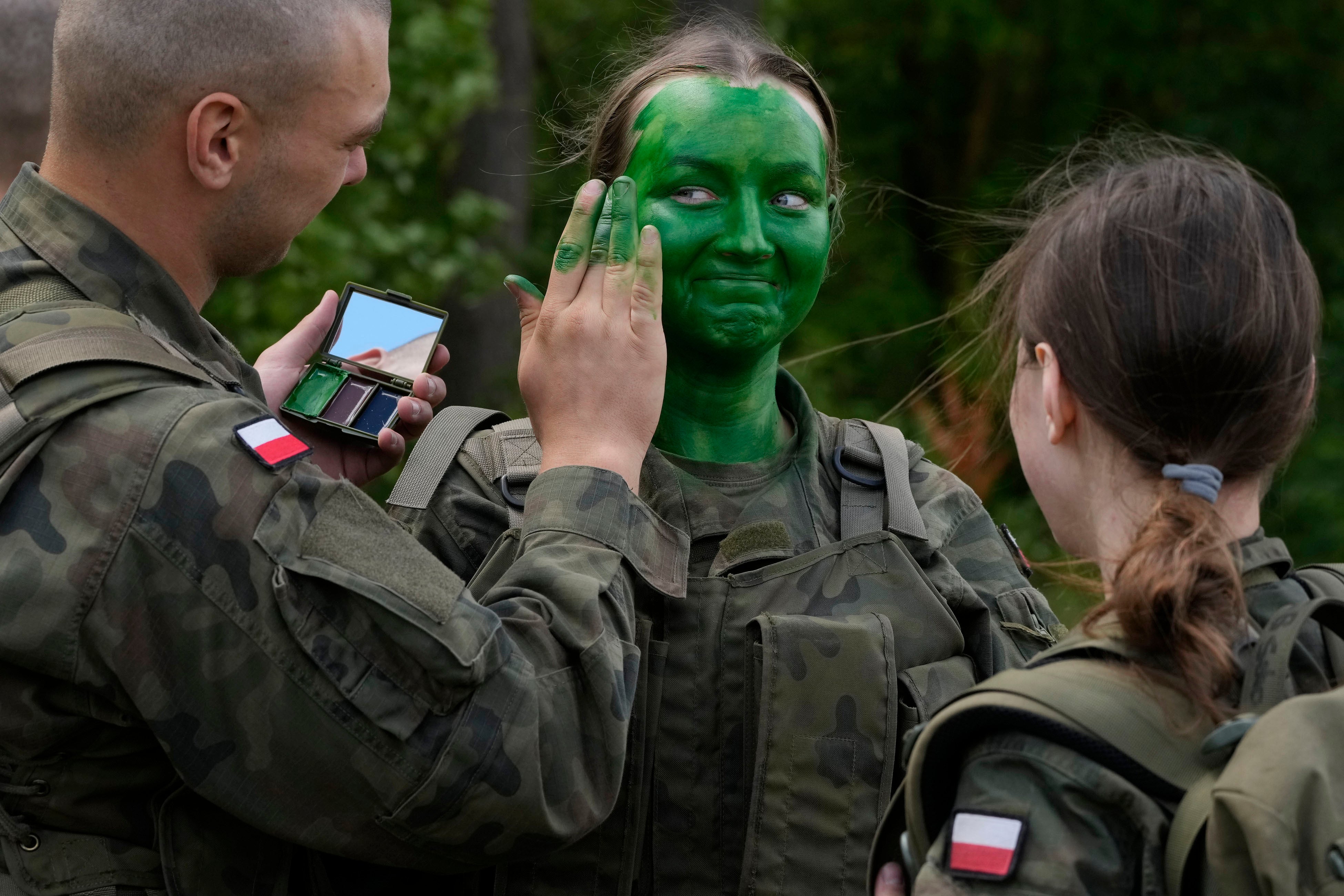 Volunteers in Poland’s army learn to apply camouflage face paint during basic training in Nowogrod, Poland