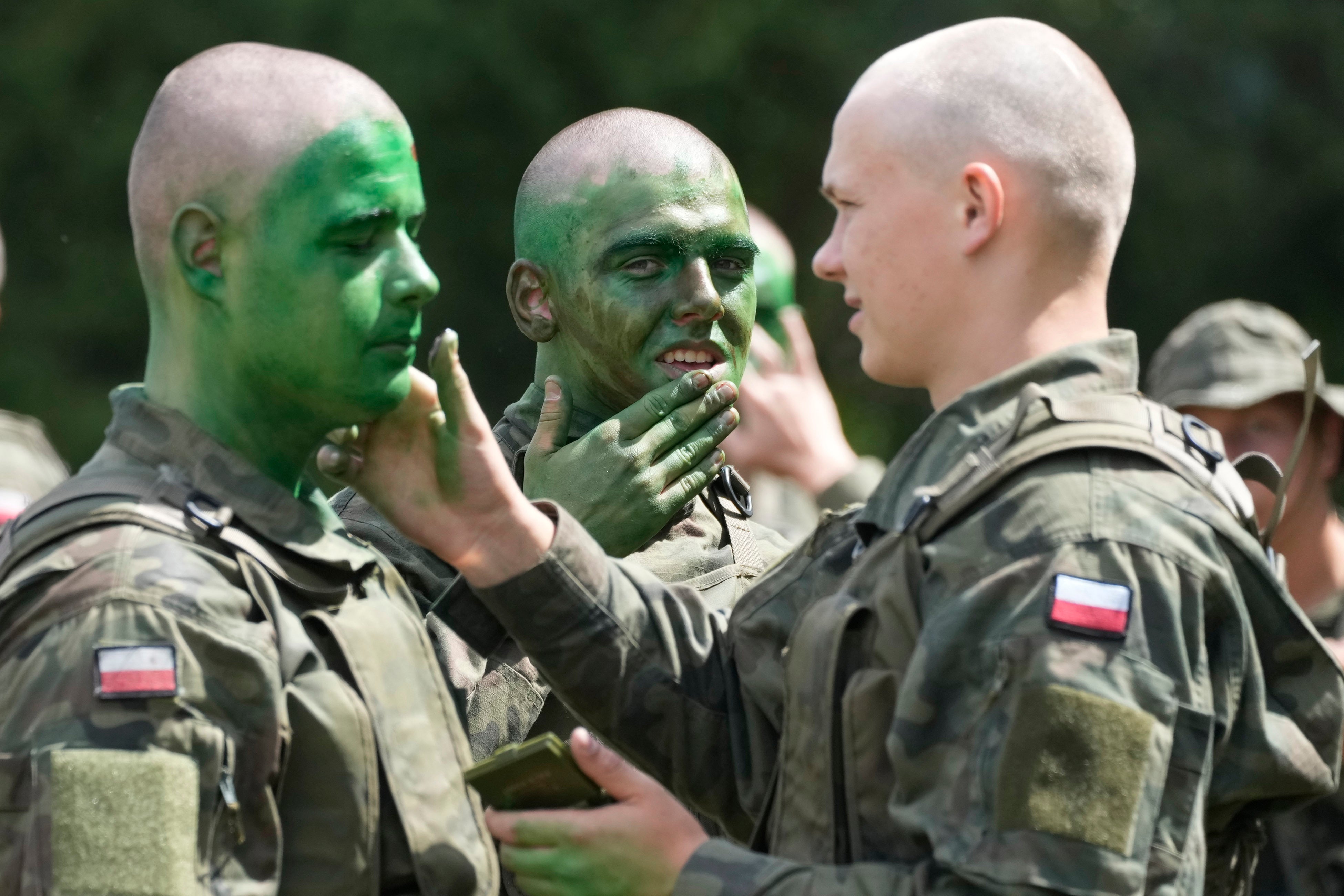 Volunteers in Poland's army learn to apply camouflage face paint during basic training in Nowogrod, Poland, on Thursday June 20