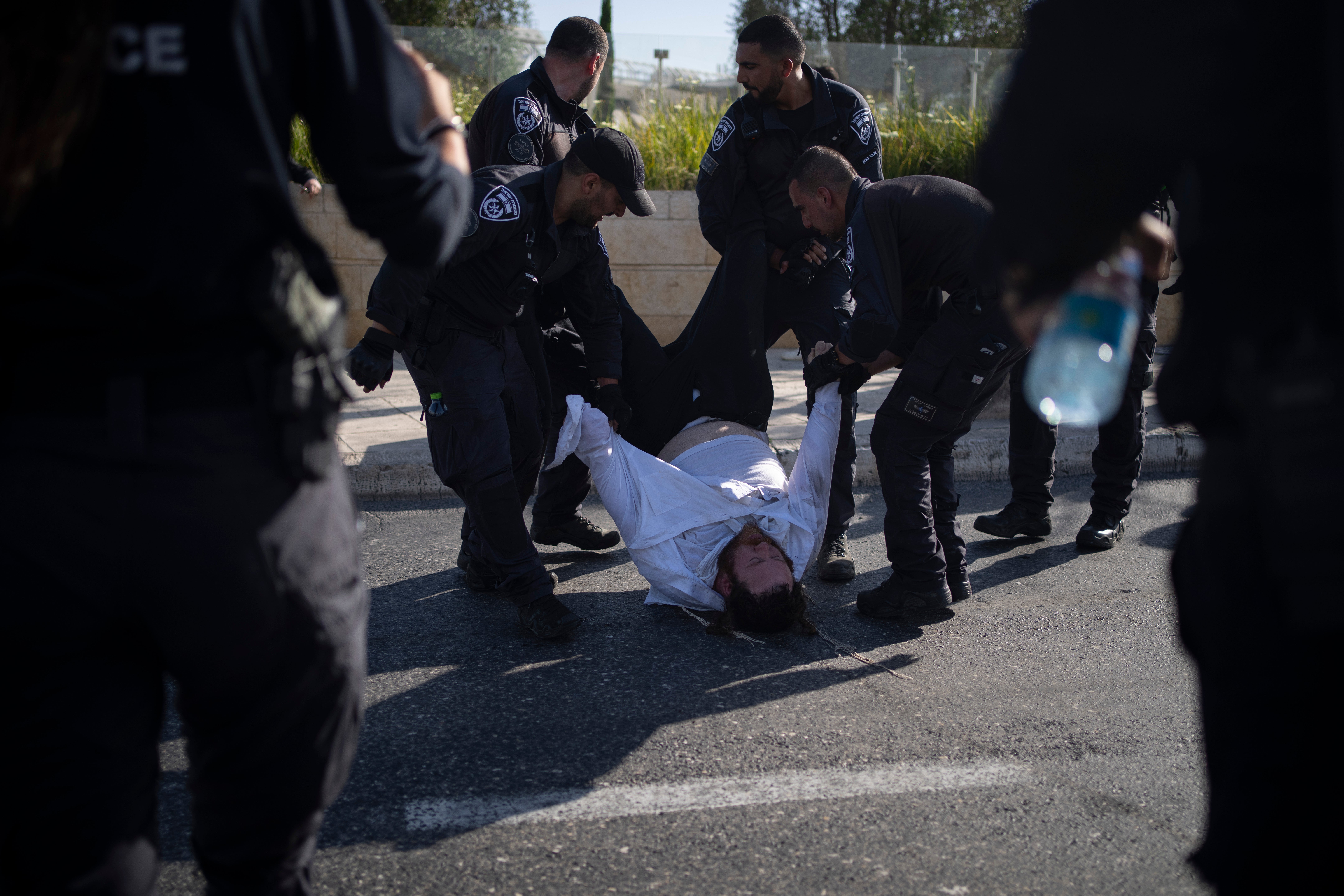 Israeli police officers remove an ultra-Orthodox Jewish man from the street during a protest against army recruitment in Jerusalem on June 2, 2024