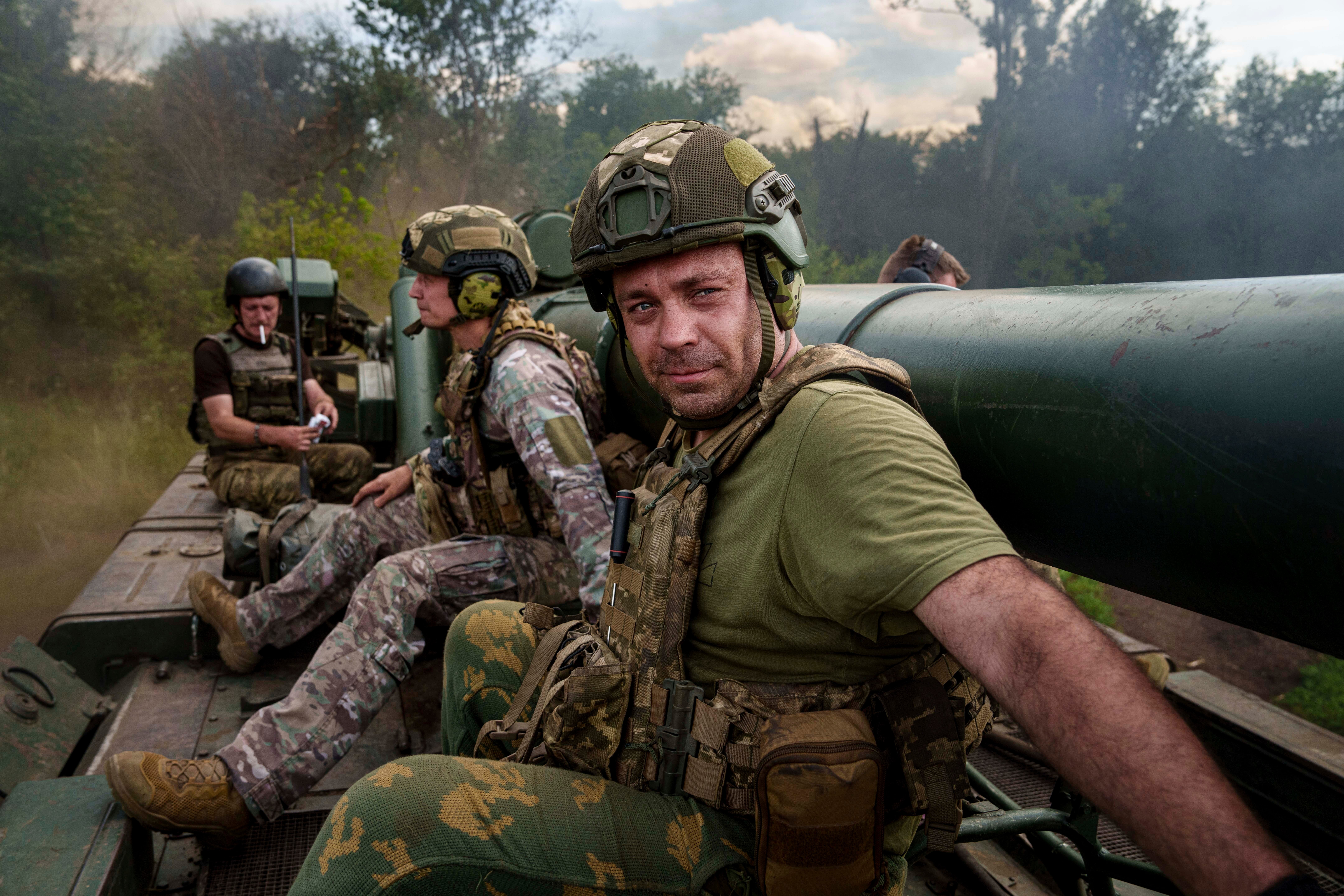 Ukrainian soldiers of 43rd artillery brigade ride atop on 2s7 self-propelled howitzer before firing towards Russian positions at the frontline in Donetsk region