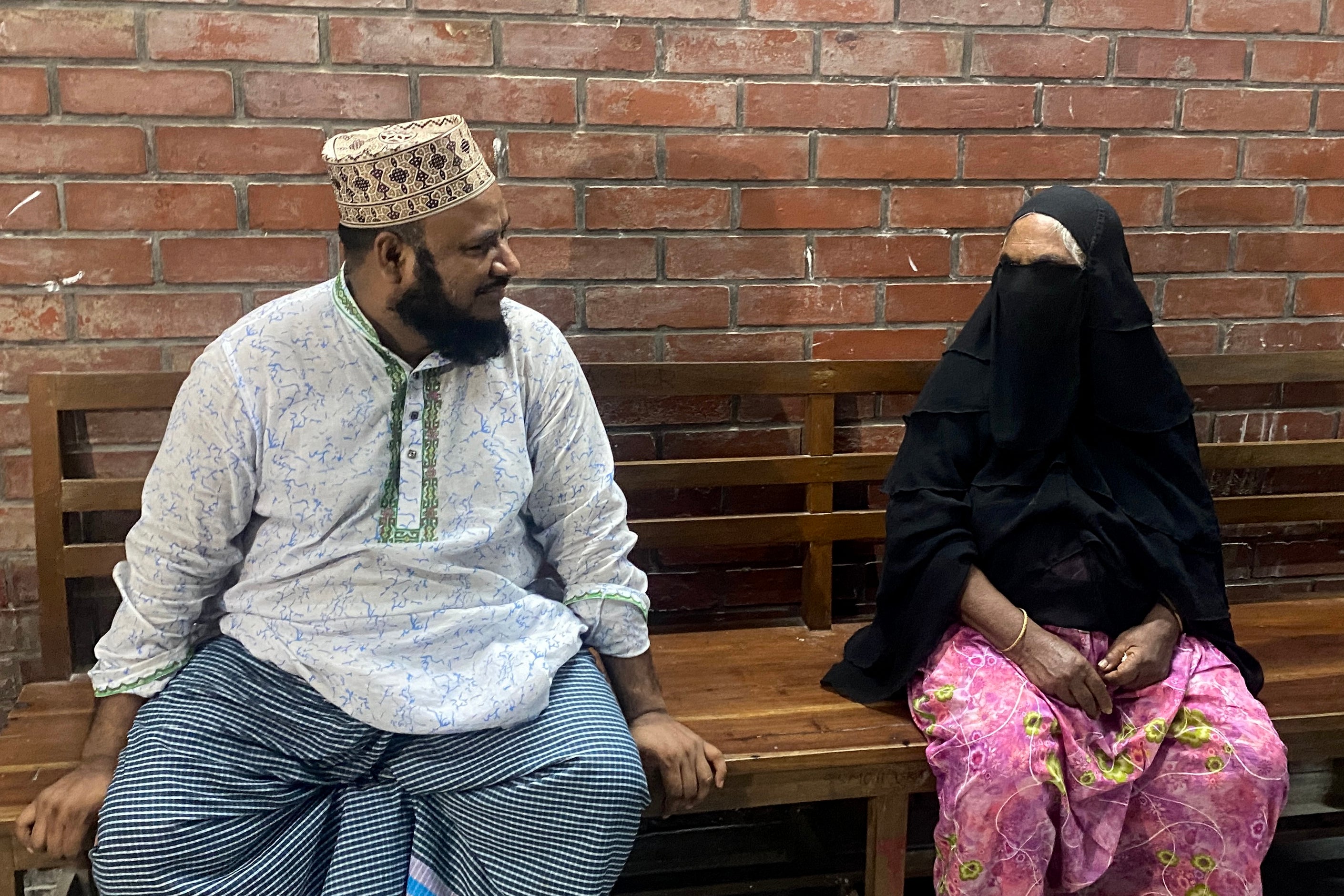 Landlord (L) and Sister of Bangladesh’s hangman Shahjahan Bouya sit at a hospital bench as they wait to receive Bhuiyan’s body