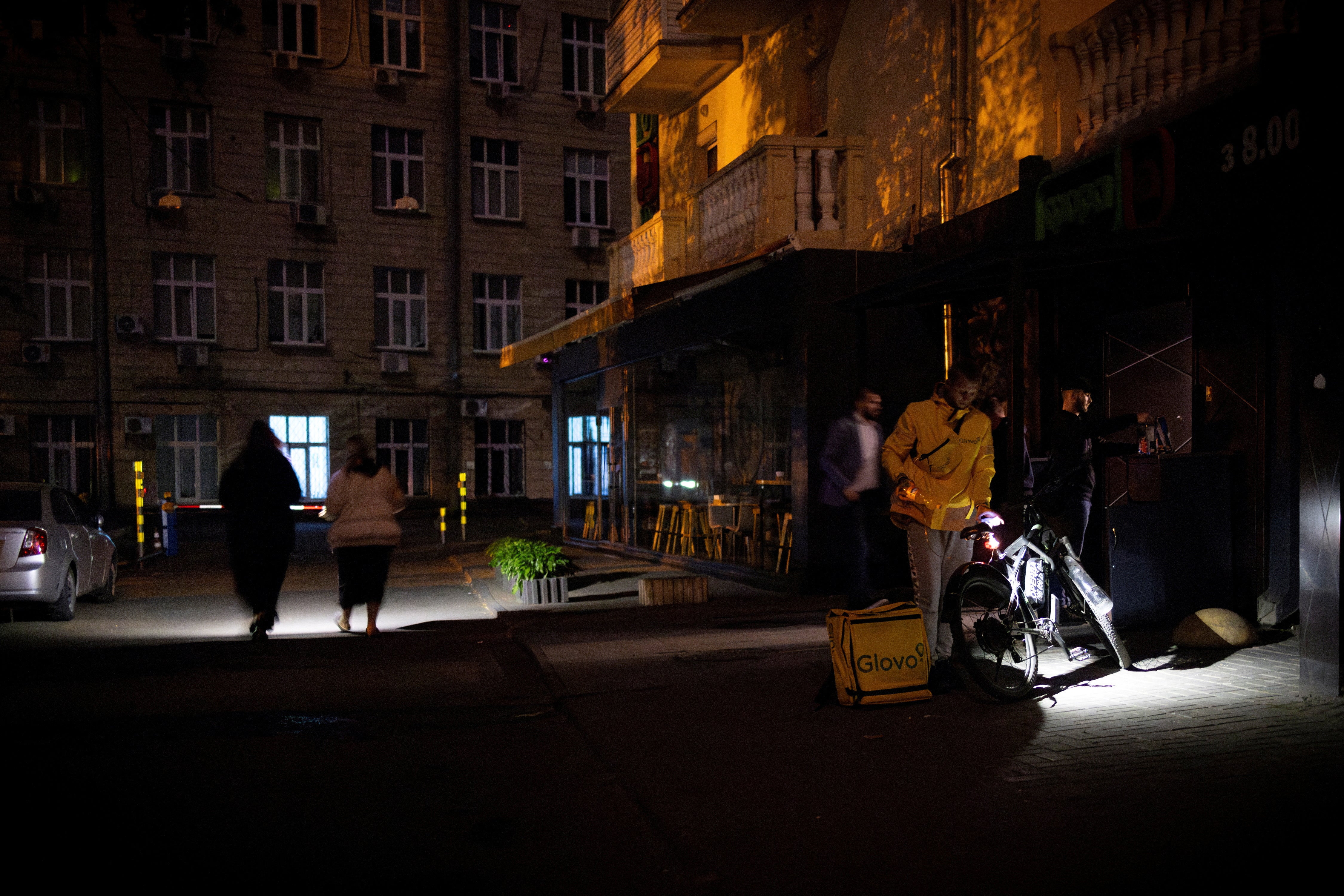 People use flashlights as they leave a supermarket during a partial power outage in the Ukrainian capital Kyiv last month